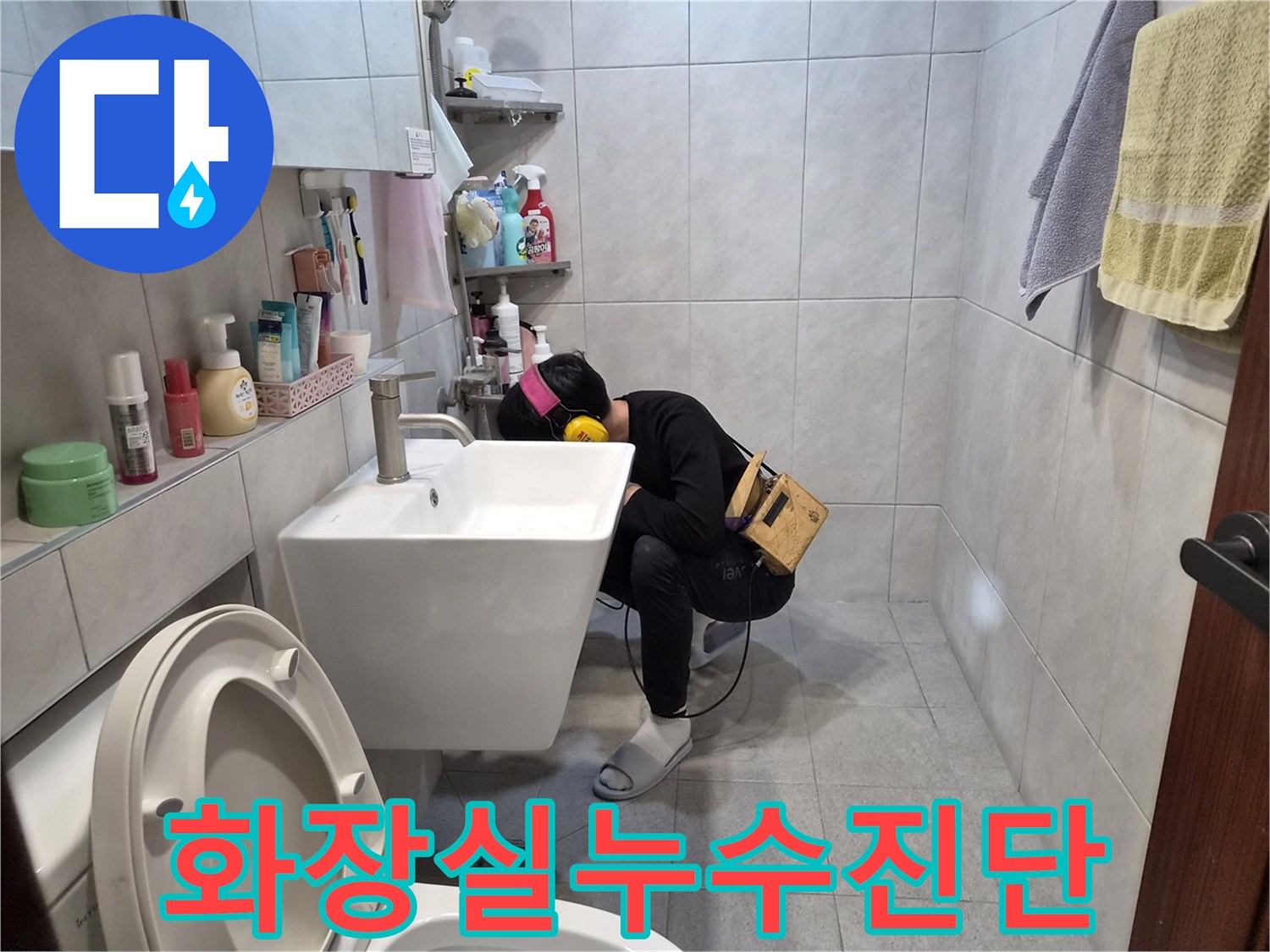 욕실-세면대-아래에서-누수-소리를-찾기-위해-집중적으로-청음-작업을-수행하는-모습입니다.