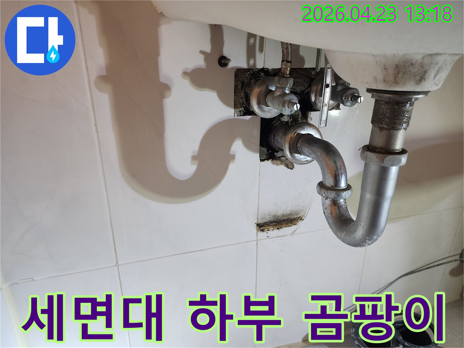 이 이미지는 양주 삼숭동 아파트 세면대 하부 배관에서 발생한-누수로 인해 벽면에 생긴 곰팡이와 물자국을 보여주며-환경 개선의 필요성을 강조합니다.