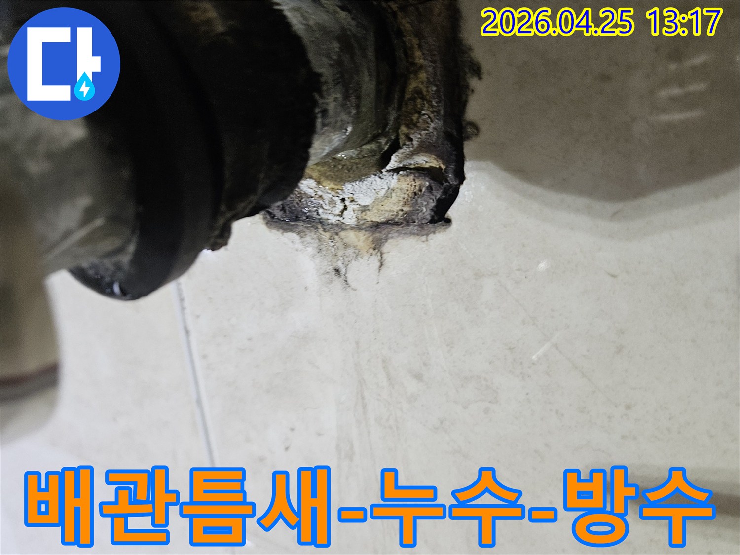 배관과 벽면 사이의 틈새에서 누수가 발생하여 주변이 오염된 모습을 보여주는 이미지입니다-틈새 보수와 방수 처리가 시급합니다.