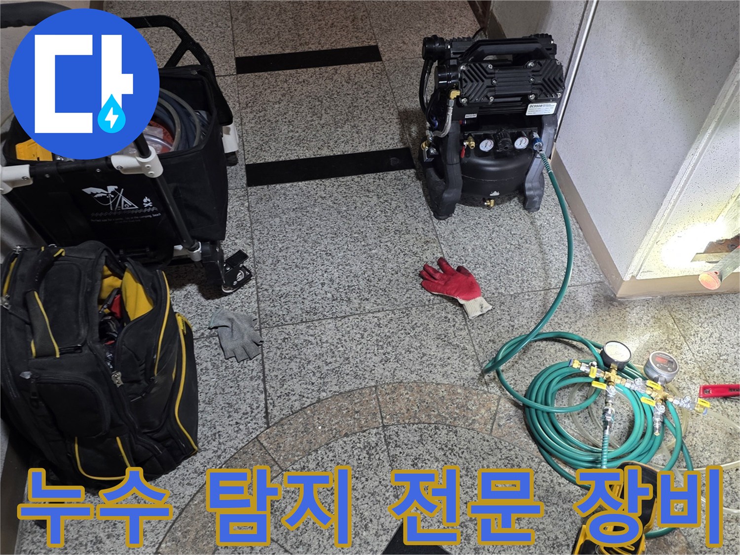 바닥 타일 위에 놓인 누수 탐지용 공압기와 가스 호스