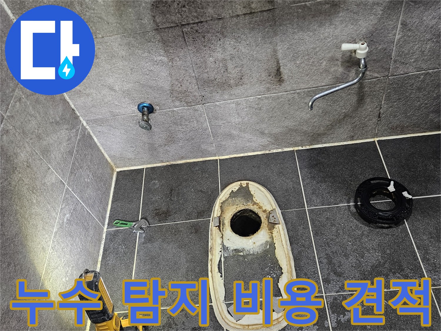 변기가 제거된 욕실 바닥의 배수구와-주변 타일에 스며든 물의 흔적을-손전등으로 밝혀 누수 탐지 후 합리적인 견적을 위한 현장 확인 모습입니다.