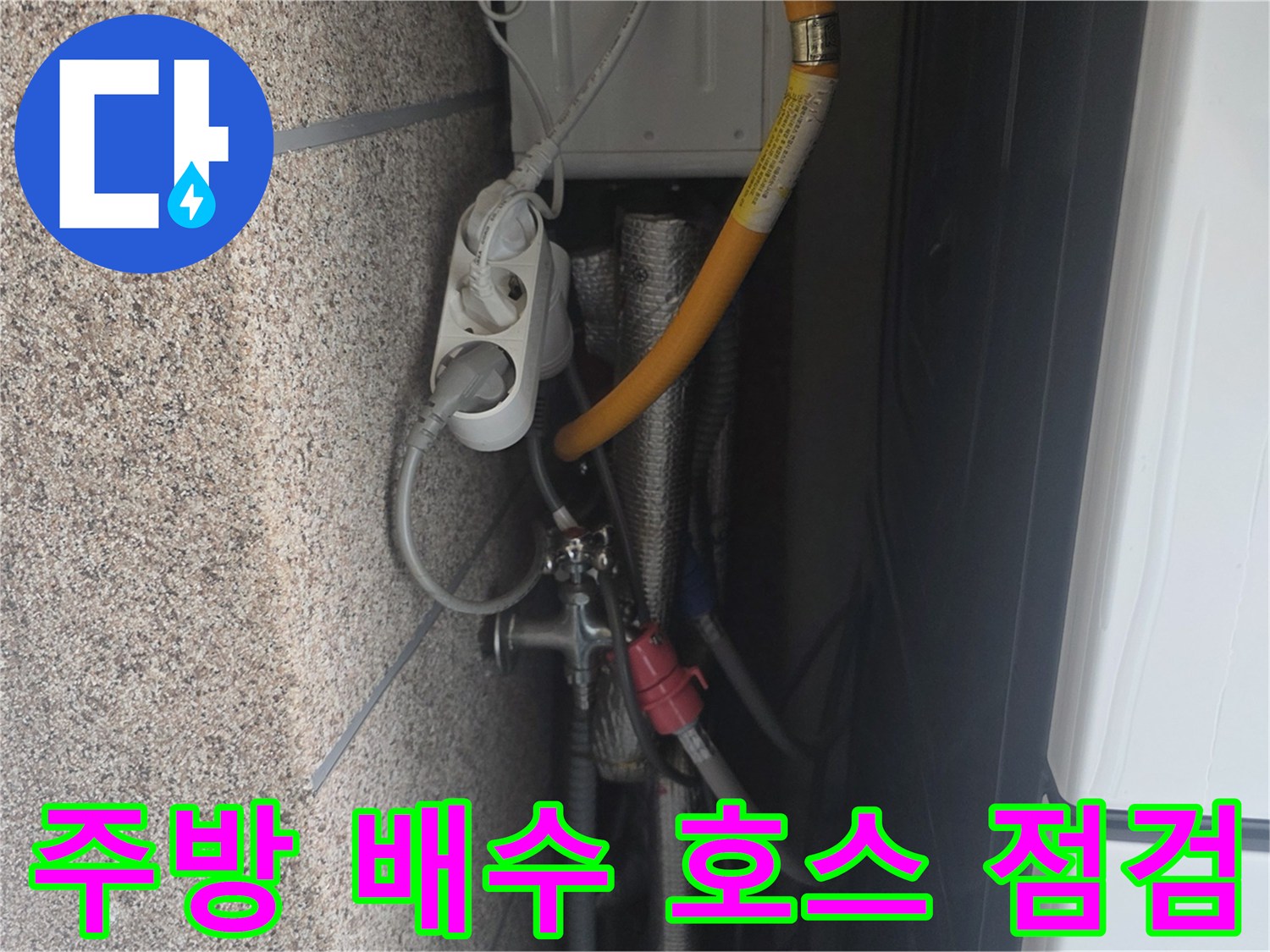 싱크대 하부장 내 노란색 배수 호스와 금속 연결 부위의 모습