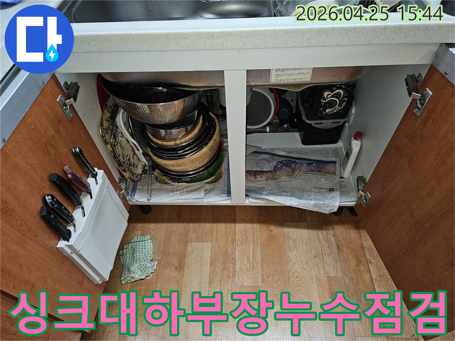 싱크대 하부장 내부-누수 점검을 위해 열린 모습-그릇과 배관이 보입니다.