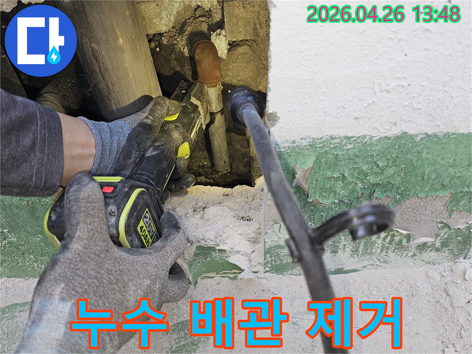 누수 전문 엔지니어가-벽 속에 숨겨진-손상된 배관을-전동 공구로-조심스럽게 잘라내고 있습니다.