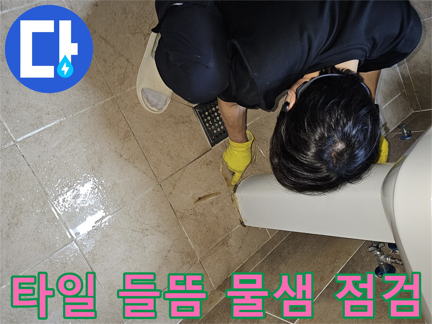 전문 엔지니어가-노란 장갑을 끼고-욕실 바닥의 젖은 타일과-들뜬 타일 틈새를-손가락으로 가리키며-누수 지점을 면밀히 확인하는 장면