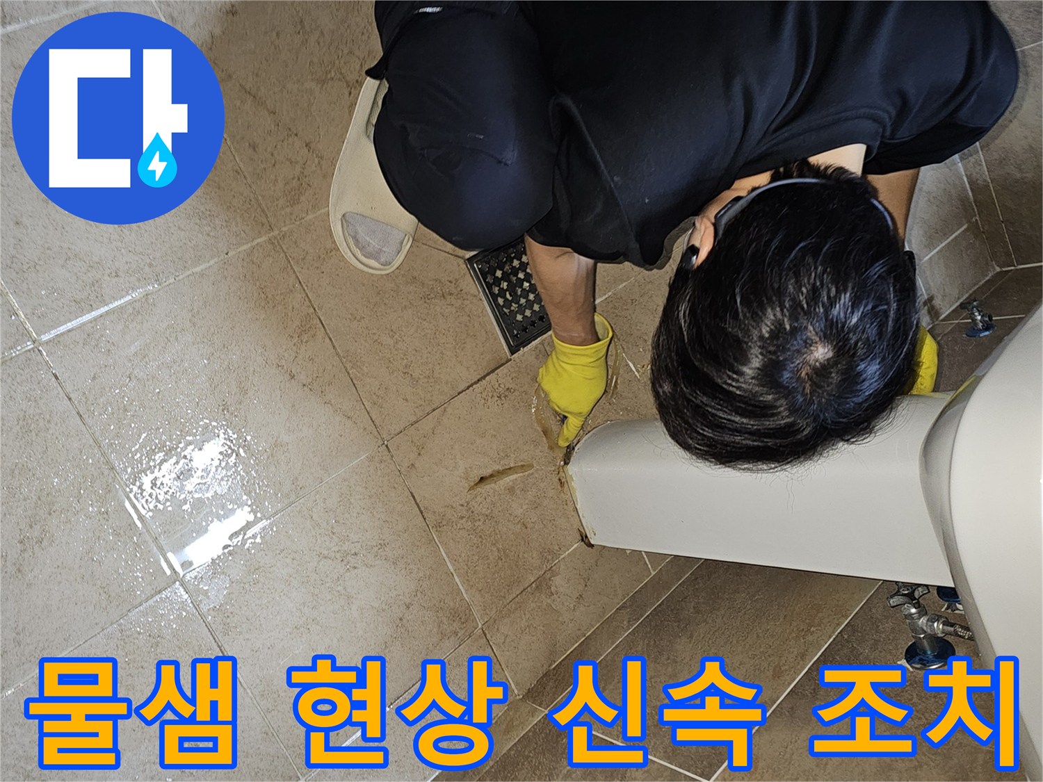 전문 엔지니어가-노란 장갑을 끼고-욕실 바닥의 젖은 타일과-세면대 하단부를-집중적으로 관찰하며-누수 지점을 신속하게 확인하고 있습니다