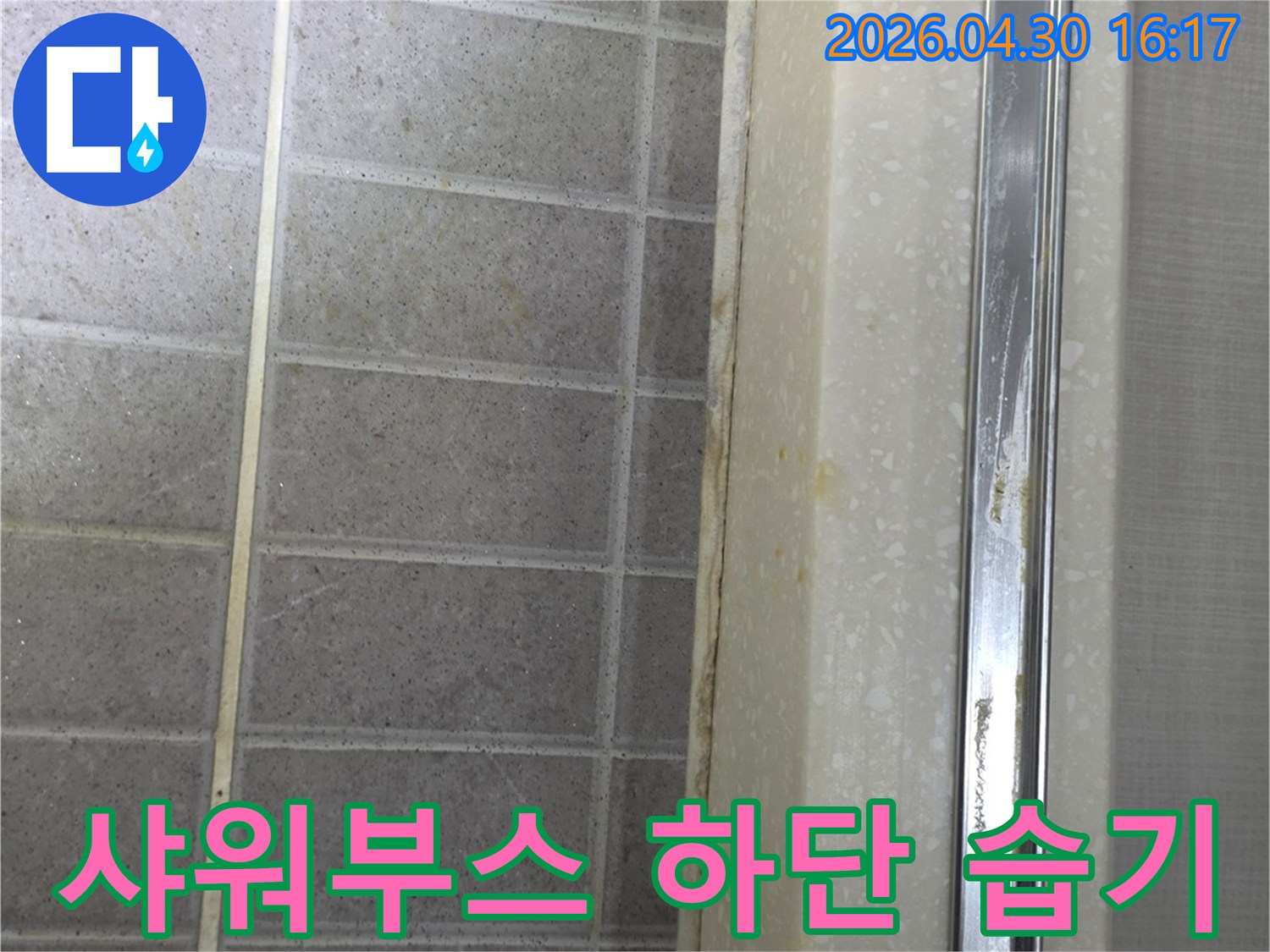 샤워부스 하단부 타일과-경계면에 습기로 인한 오염이 발생한 모습입니다