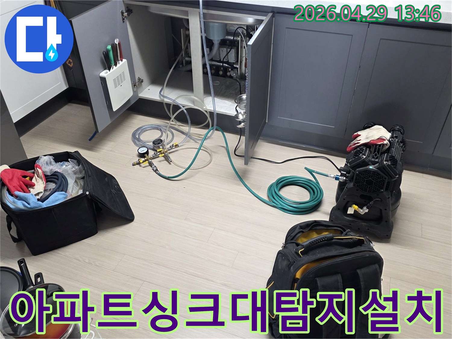 동안구 아파트의 주방 싱크대 하부에서-누수 탐지를 위한-압력 게이지와 호스-그리고 공기 압축 장비를-설치하는 작업이 진행 중입니다