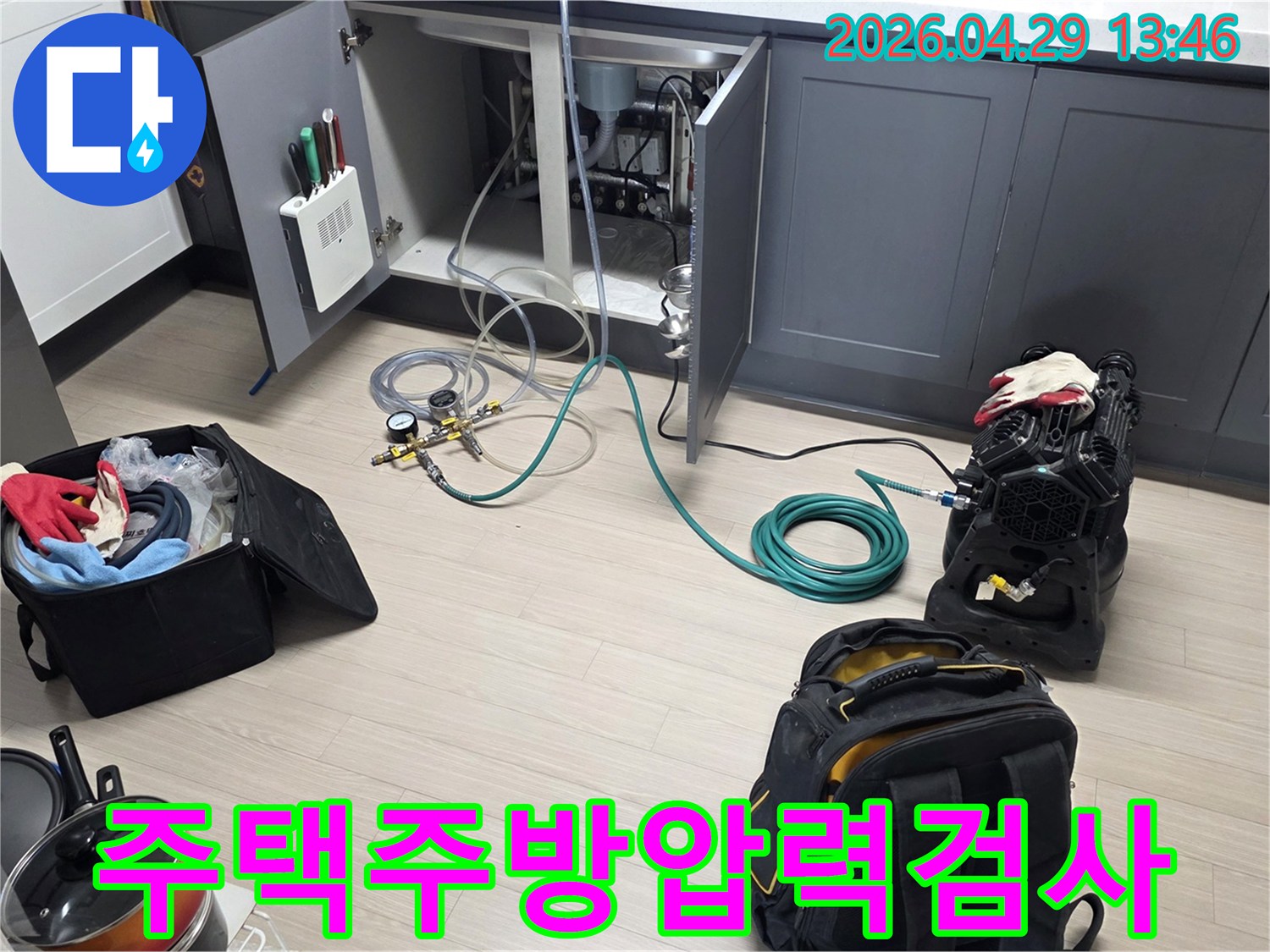 동안구 주택의 주방 싱크대 하부에서-누수 확인을 위한-배관 압력 검사 장비와-호스를 연결하여-테스트를 준비하는 모습입니다
