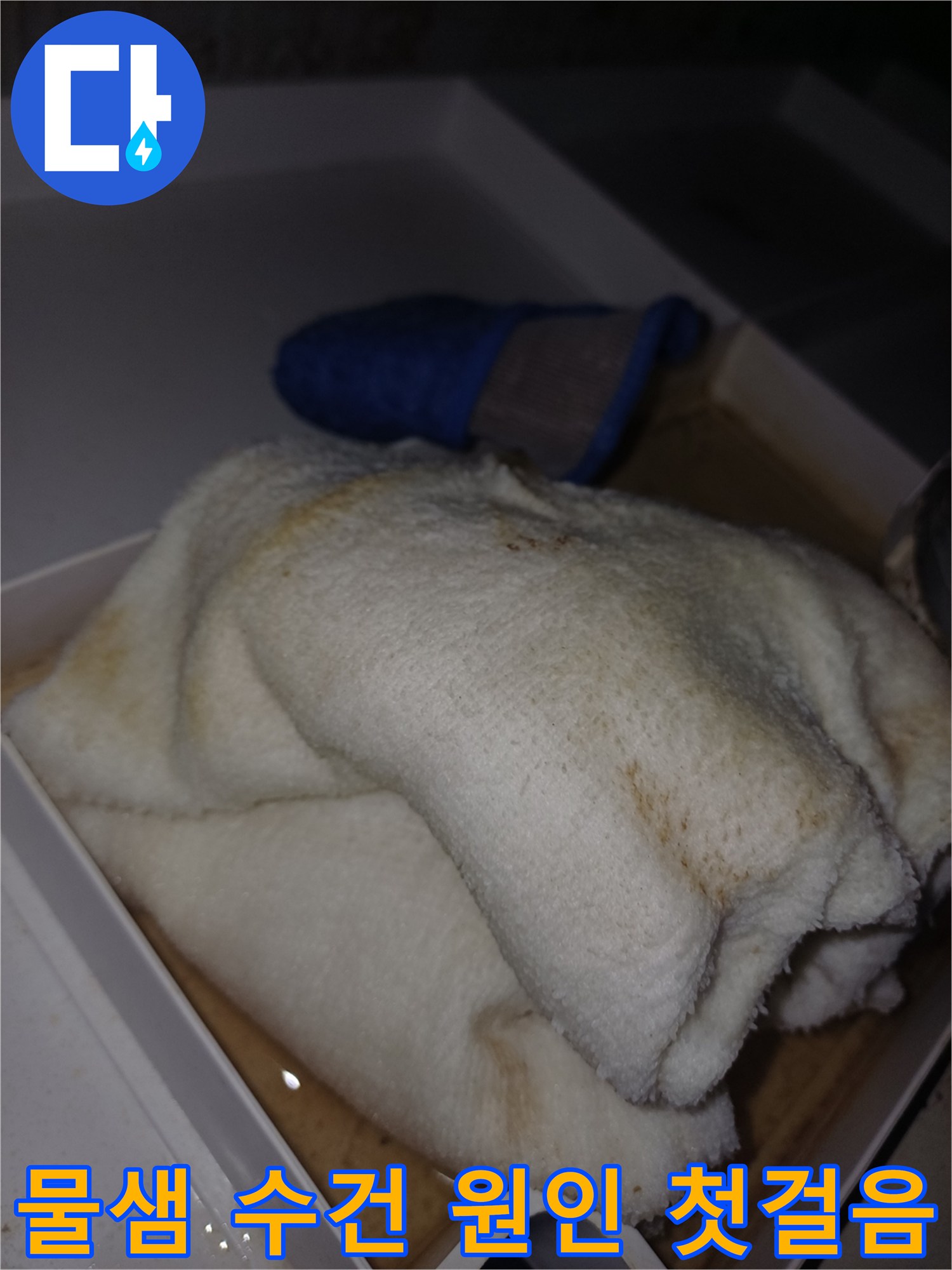 물에 젖어 얼룩이 생긴 수건이 상자 안에 놓여 있는-누수 피해가 진행 중임을 보여주는 현장 사진입니다.