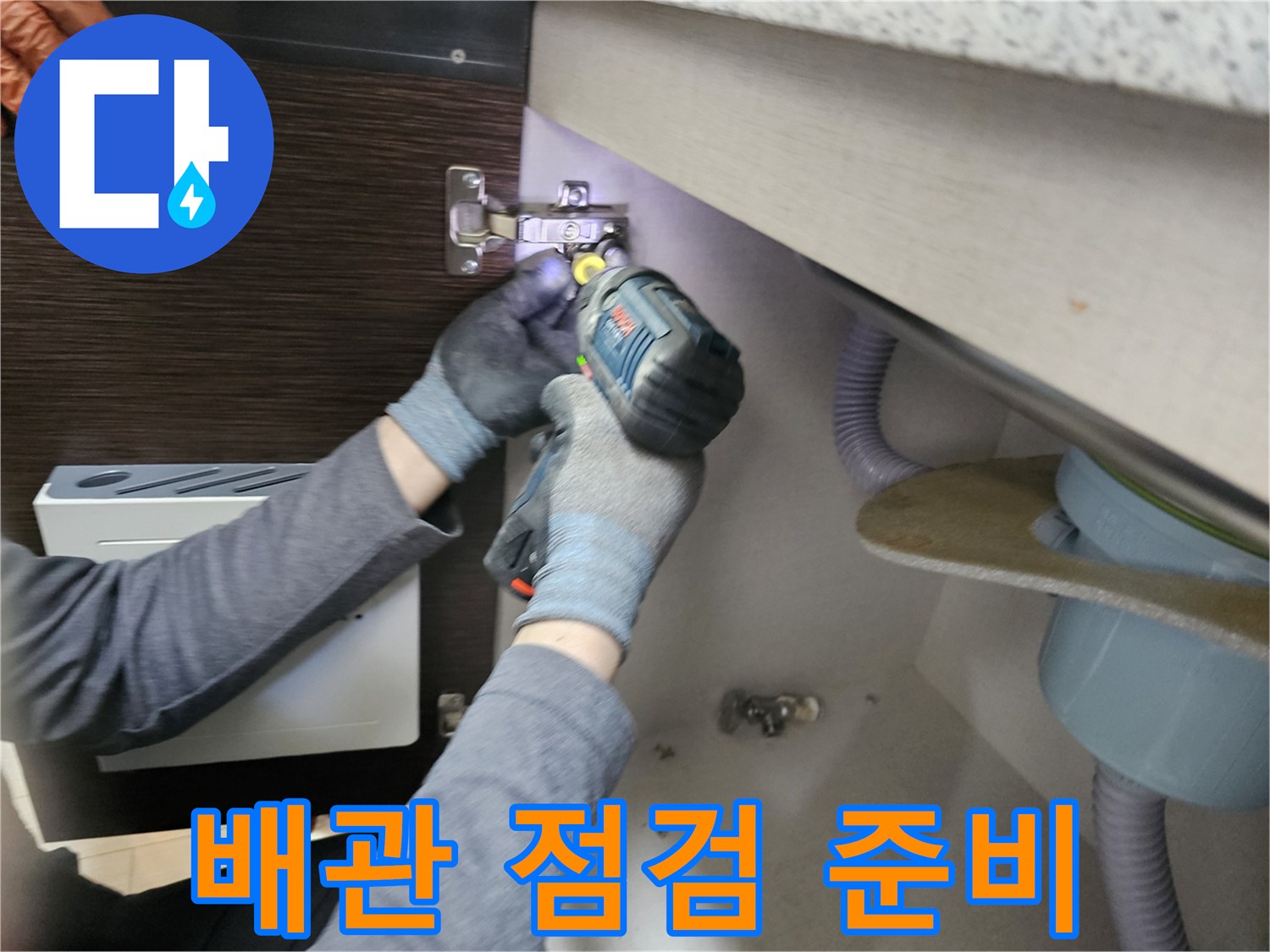 누수 엔지니어가-배관 점검을-위해-싱크대 하부장-패널을-분리하는-작업