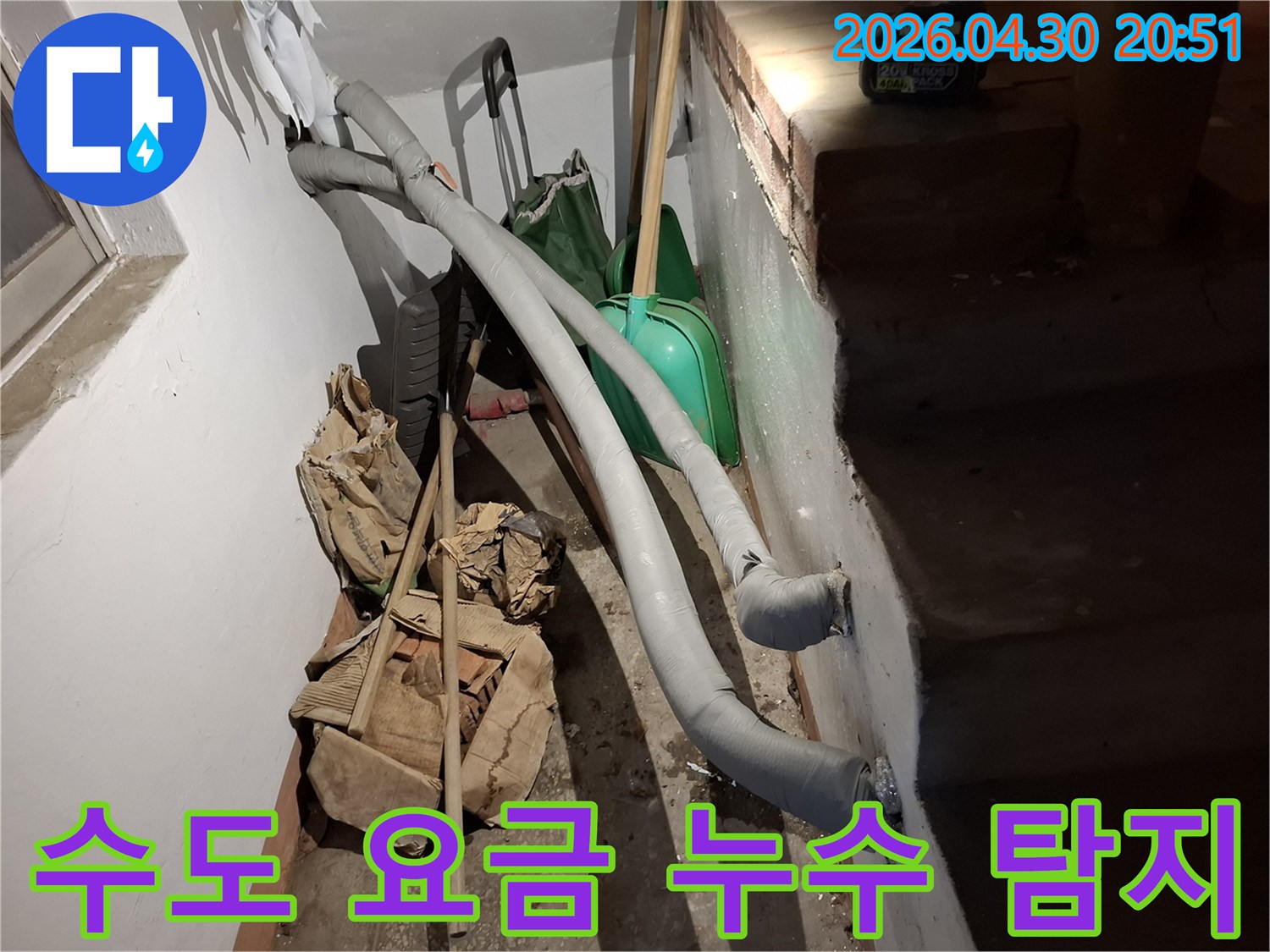 이 이미지는 지하 공간에 설치된 단열 처리된 배관과-주변에 놓인 공사 자재들을 보여줍니다.