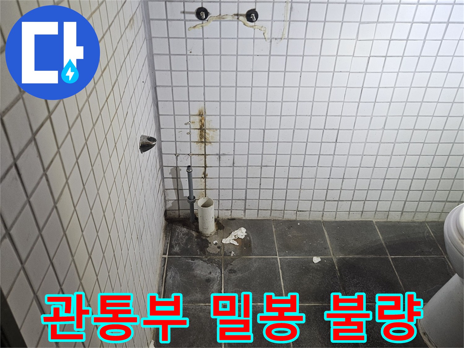 세면대 제거 후-욕실 검은색 타일 벽면에-노출된 하수 배관의-벽면 관통부 밀봉 불량과-주변 누수 흔적을-정밀하게 진단하는-누수 전문가
