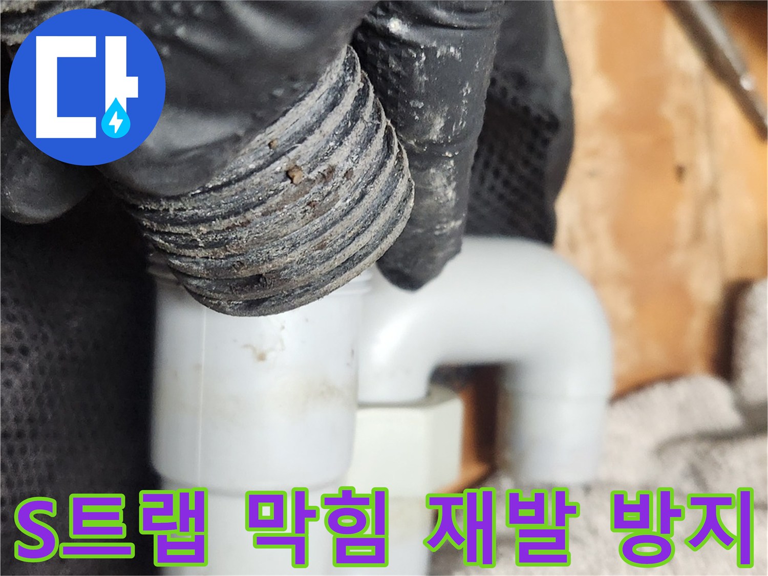 검은 장갑을 낀 손이-S트랩 배관을 분리하여-막힘 재발 방지를 위한 클리닝 작업을 진행하고 있습니다