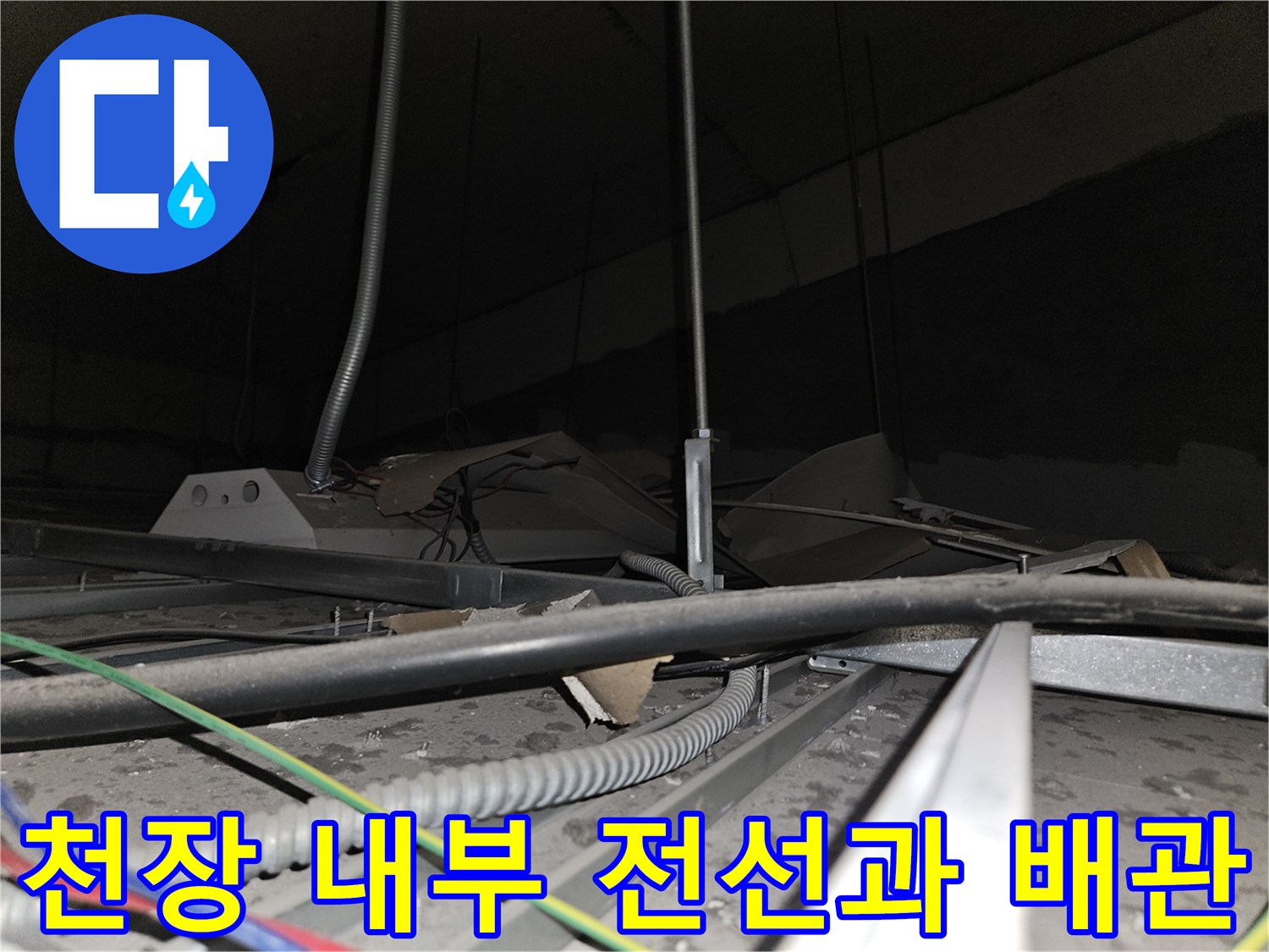 천장 텍스 사이로 보이는-전기 배선과 금속 배관 구조물