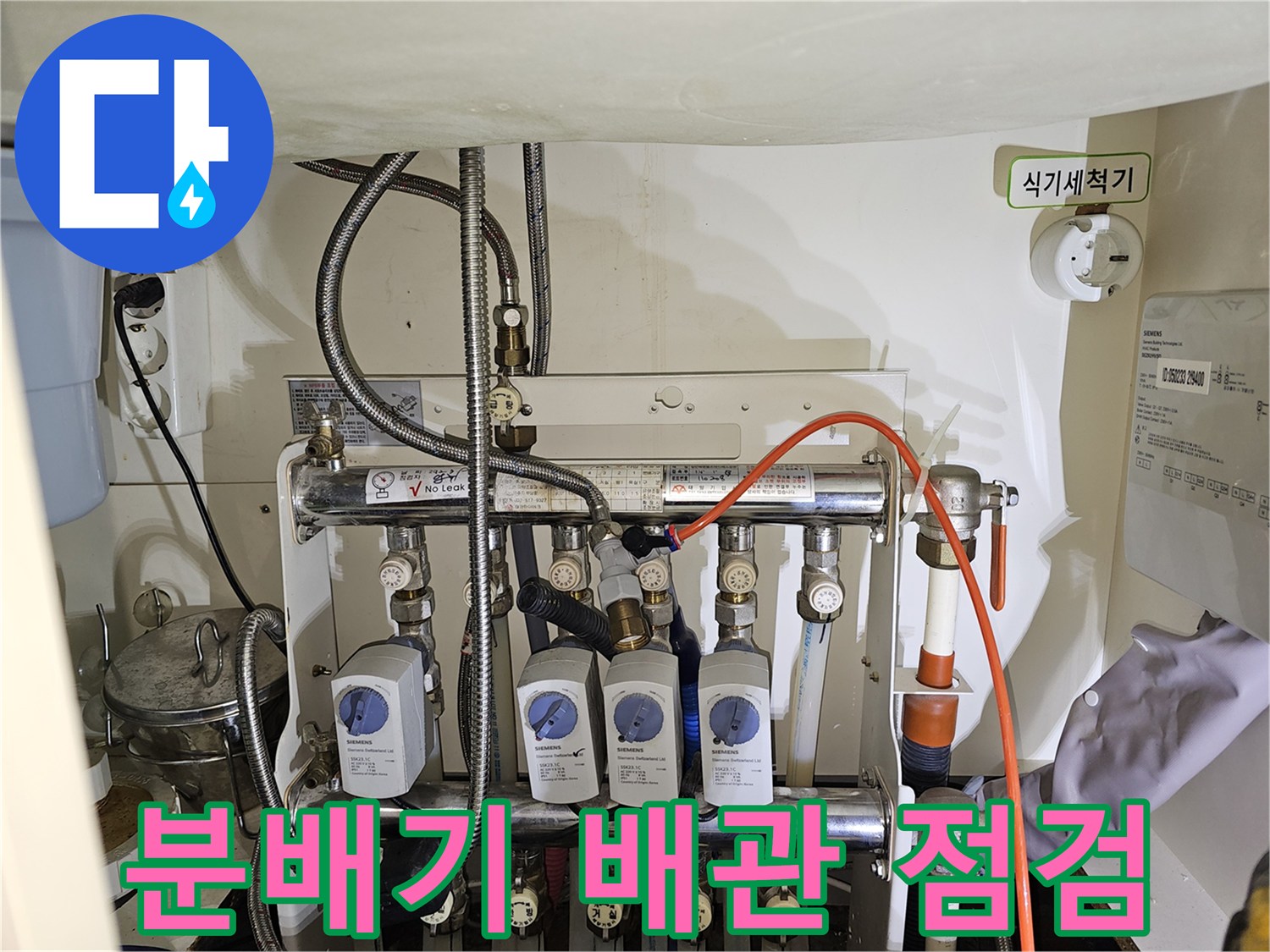싱크대 하부장 내부의 분배기와 각종 배관 연결 상태를 확인하는 모습