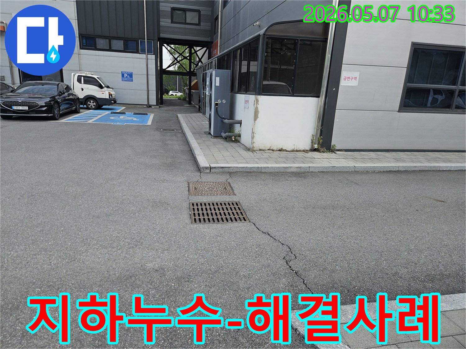 이 이미지는 의정부시 만가대길 주차장의 아스팔트 균열과-맨홀-배수구 주변의 지반 문제를 보여주며-지하 배관 누수 해결 사례를 나타냅니다.
