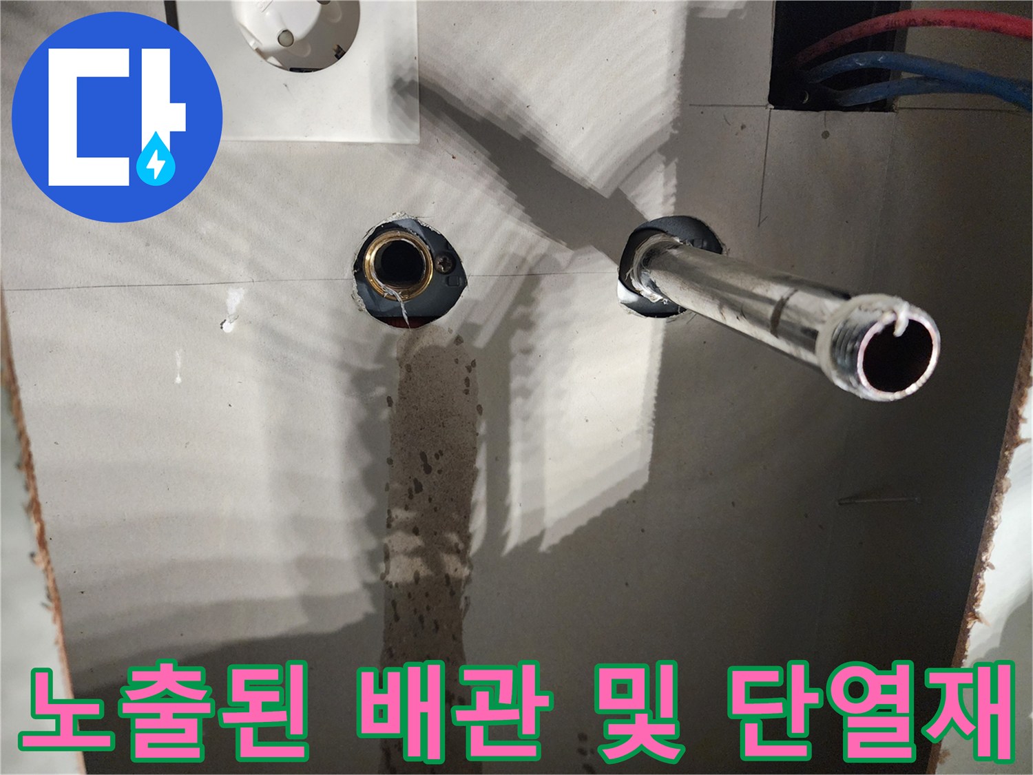 벽면 타공 부위의 금속 배관과 파란색 보온 튜브 모습