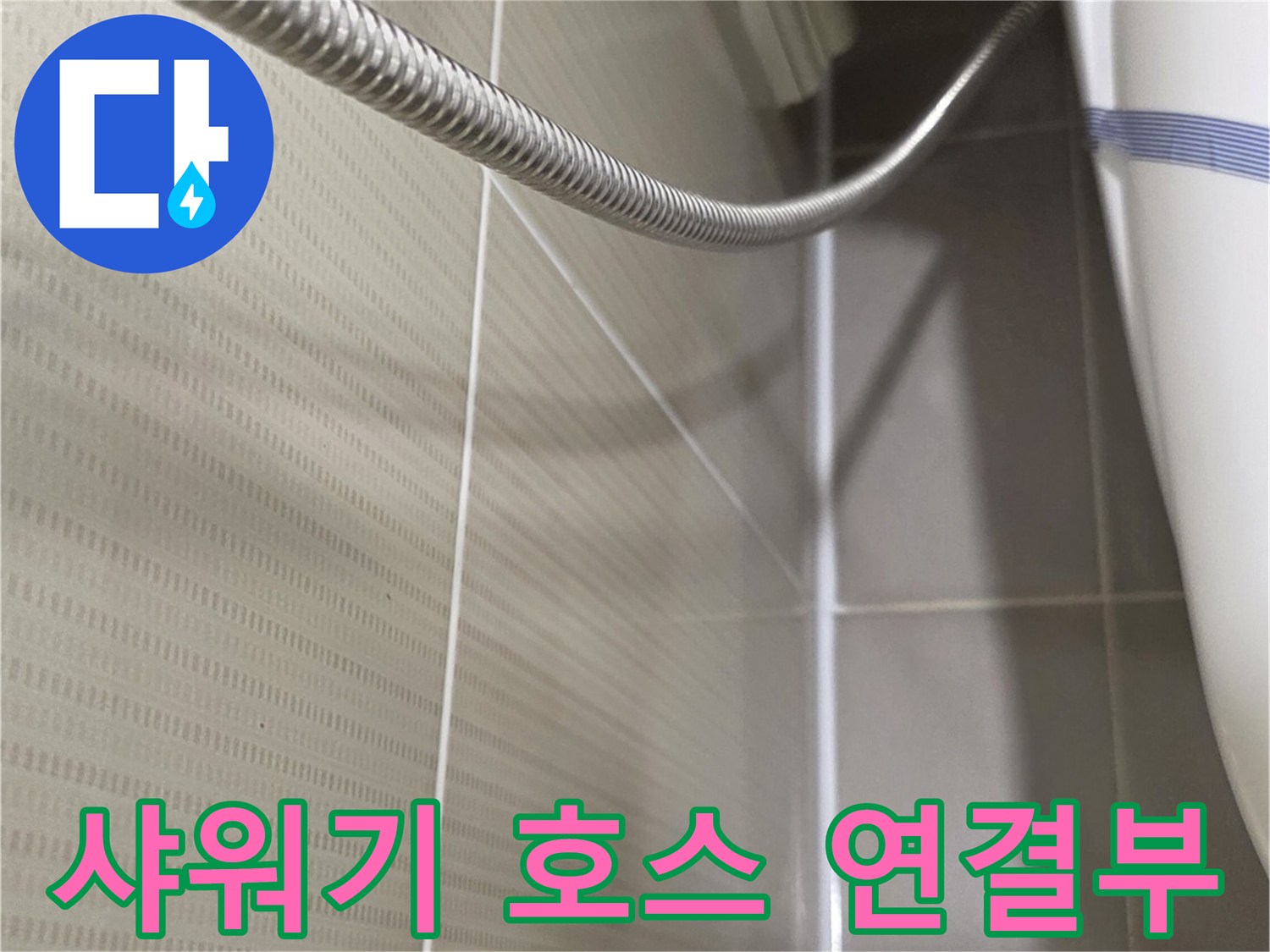 세면대 근처 샤워기 호스와 타일 벽면의 클로즈업 사진