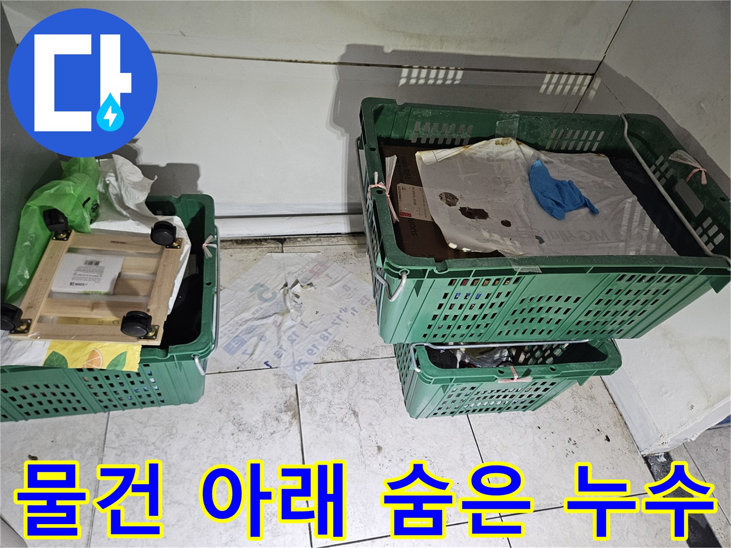 녹색 상자들이-놓여있는-벽면 하단에-누수로 인한-오염과-습기 흔적이-보이는-현장 사진으로-물건 아래-숨겨진-누수 가능성을-보여줍니다