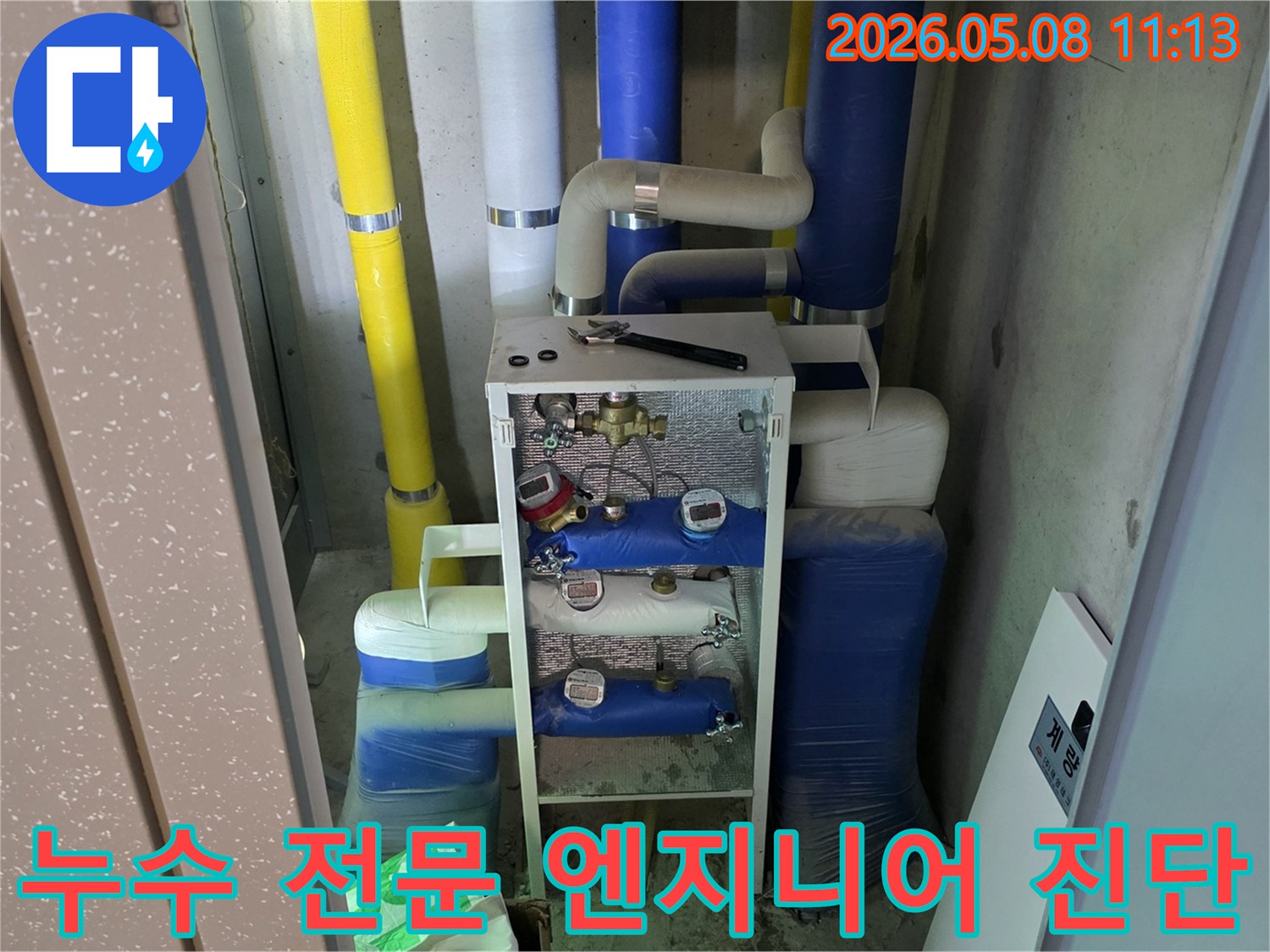 이 이미지는 건물의 유틸리티 공간에 있는-다양한 배관과 계량기-그리고 작업 도구를 보여주며-이는 누수 전문 엔지니어의-정밀 진단 과정이 진행될 준비를 나타냅니다
