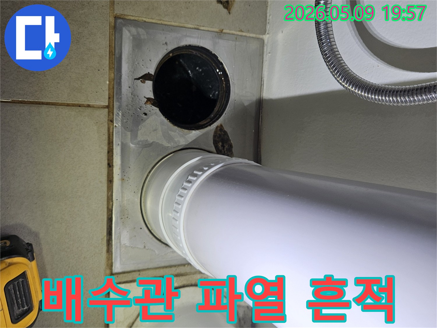 이 사진은 욕실 바닥의 배수관 주변에서 발생한 물 고임과 오염 현장을 보여주며-배관 파열 가능성을 시사합니다.