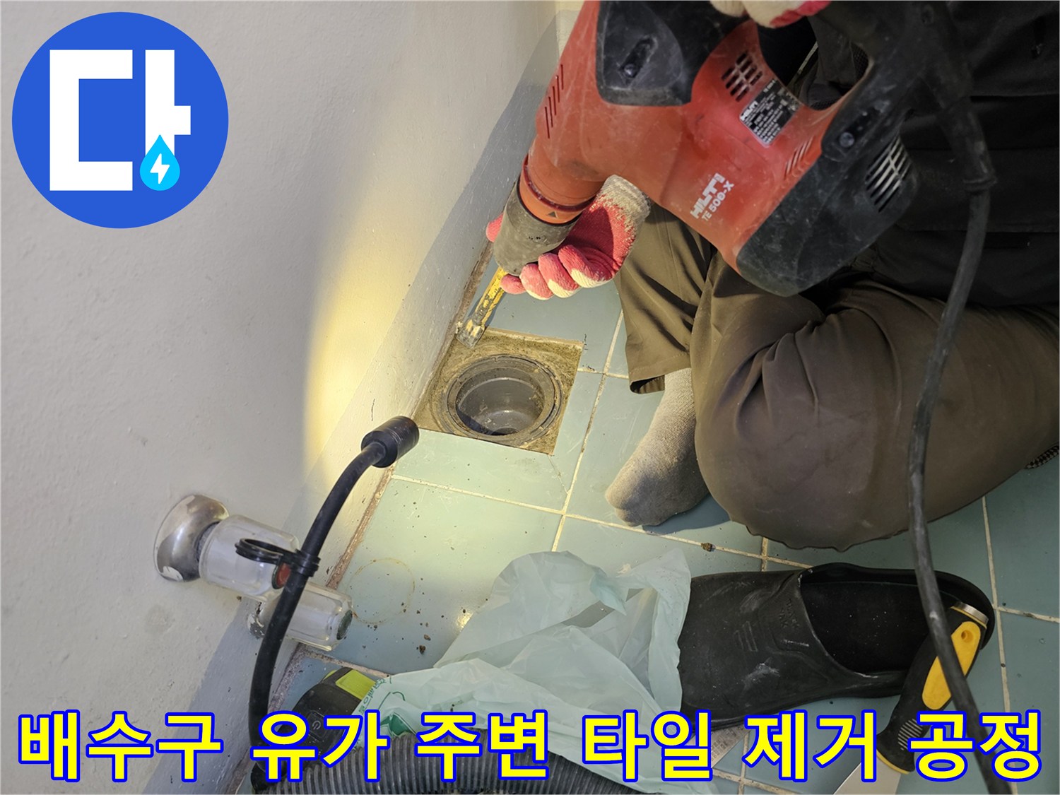 전동 드릴로 배수구 주변의 낡은 마감재를 파쇄하는 작업자
