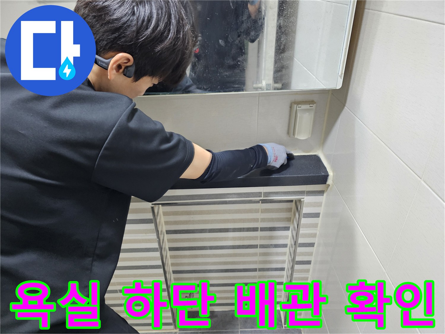 글러브를 착용한 작업자가 세면대 아래쪽의 낡은 트랩 부위를 점검하고 있습니다.