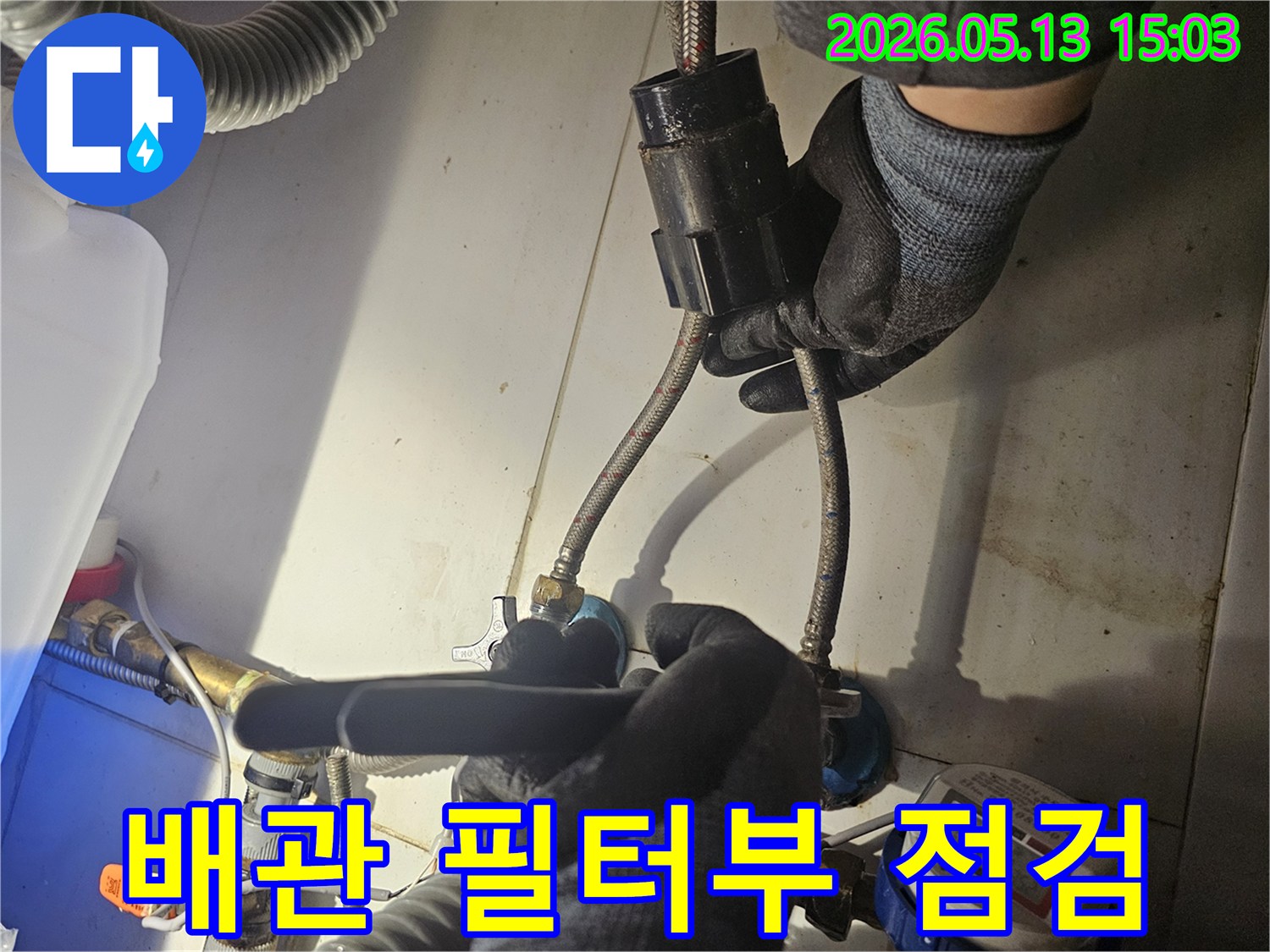 전문 기술자가-주택 내부의-배관에 연결된-검은색 필터 부위를-꼼꼼하게 점검하며-누수 여부를-확인하고 있습니다