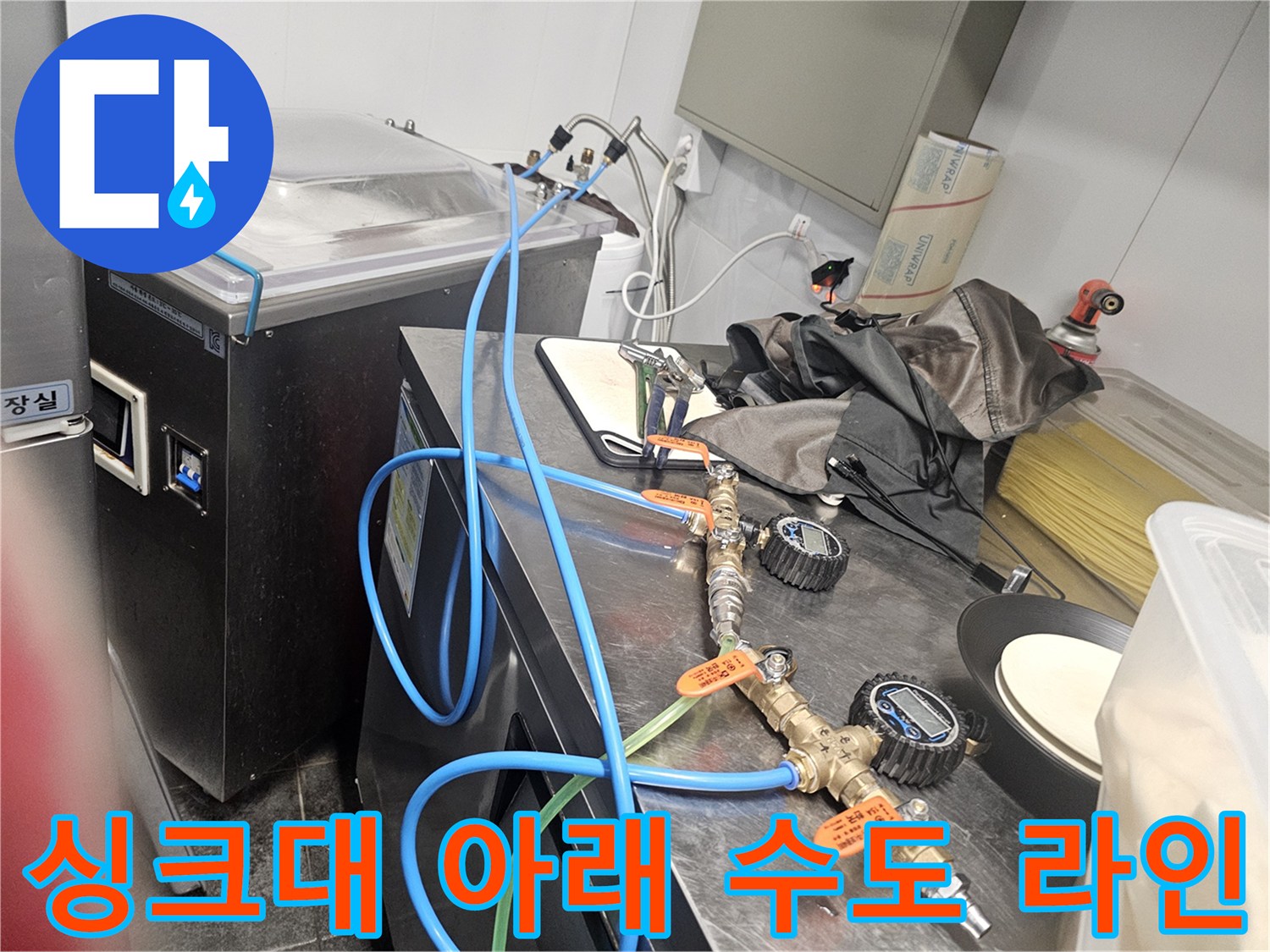 파란색 호스와 금속 밸브가 연결된 싱크대 배관 모습입니다.