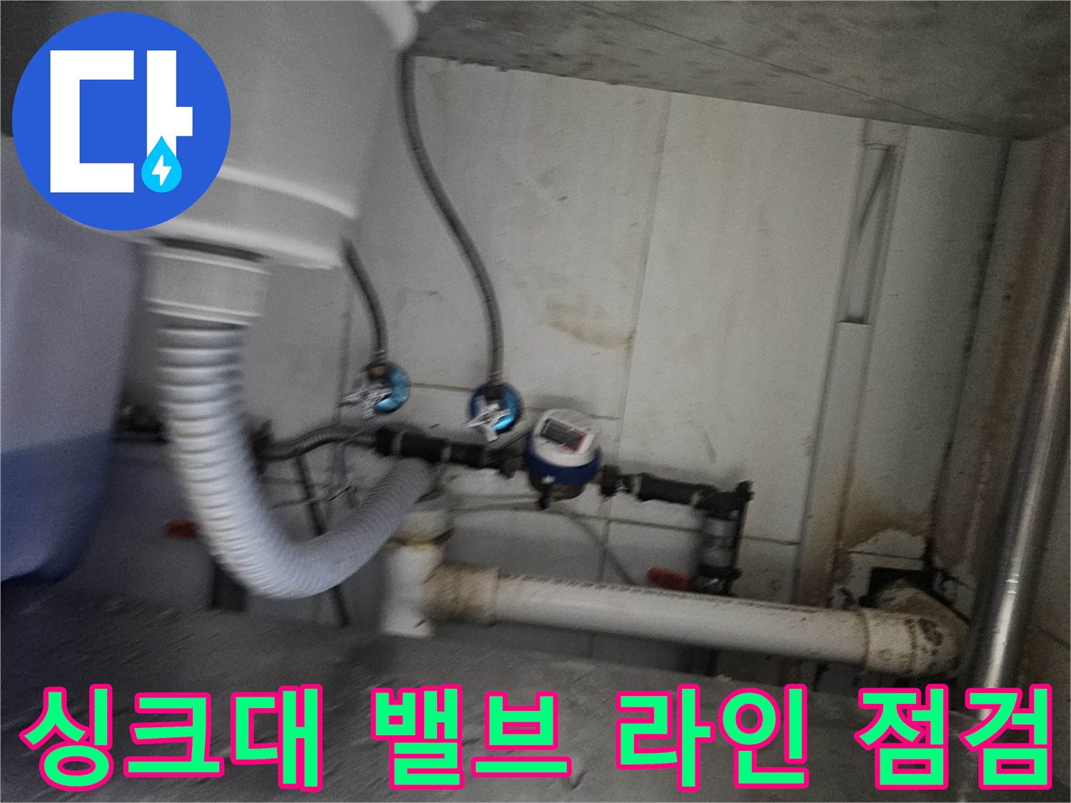 흰색 메인 배관과 파란색 밸브가 연결된 싱크대 하부 모습