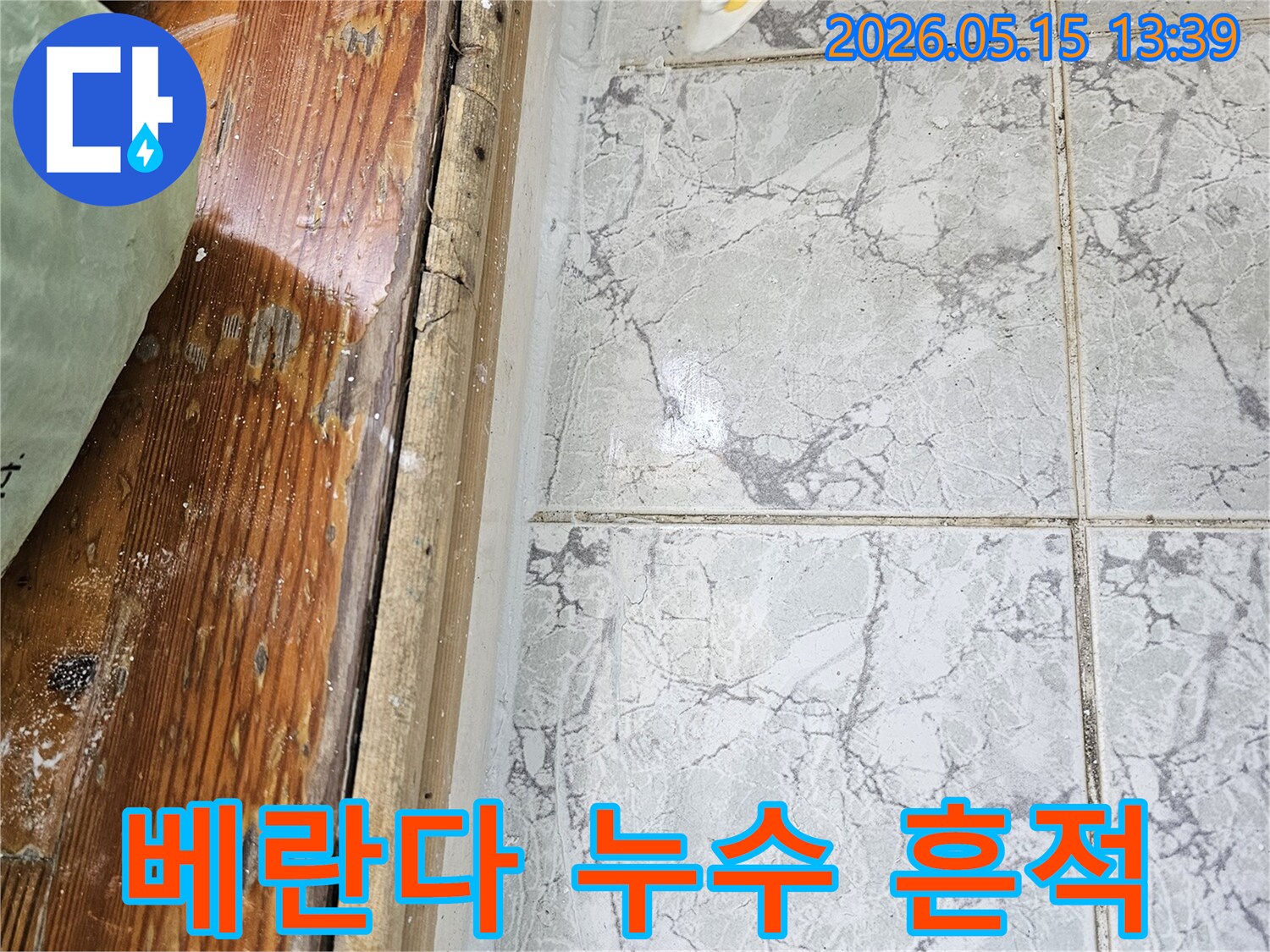 이 이미지는-의정부 신곡동 아파트 베란다에서 발생한-누수로 인해 타일과 목재 마감재가 손상된 모습을 보여줍니다