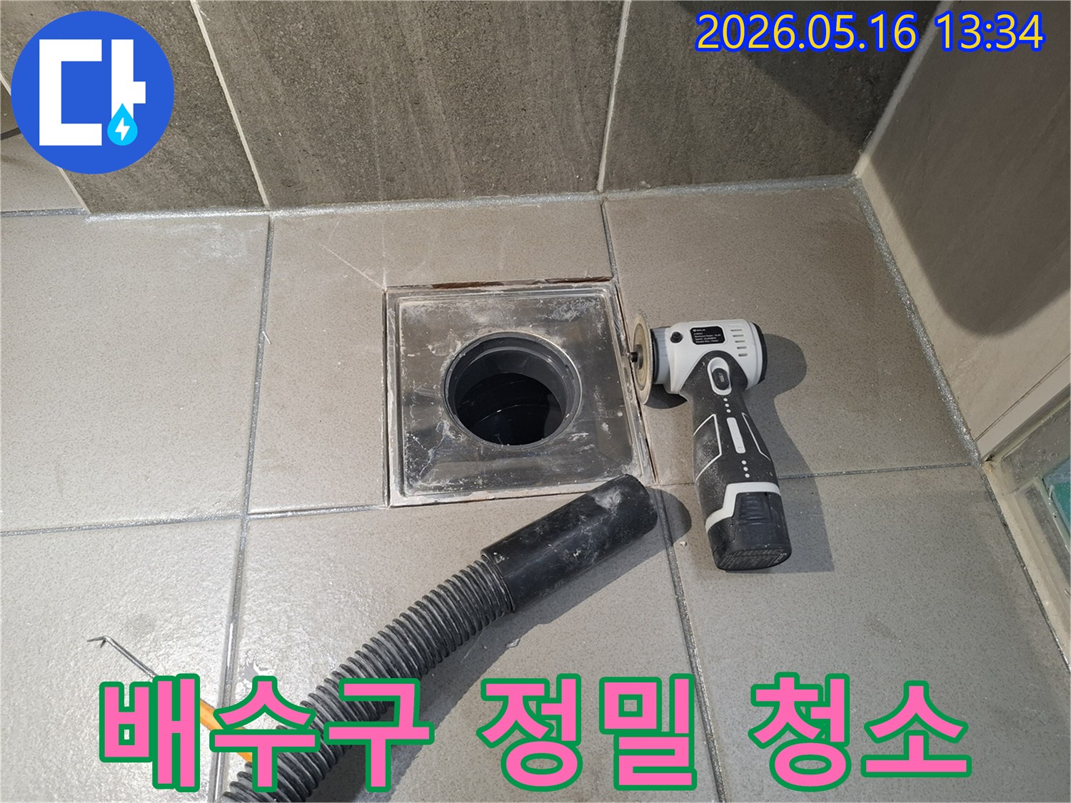 누수 엔지니어가 욕실 배수구 주변의 누수 해결을 위해-전동 공구로 이물질을 제거하고-흡입 호스로 물기를 건조하는 정밀 청소 작업을 진행 중입니다