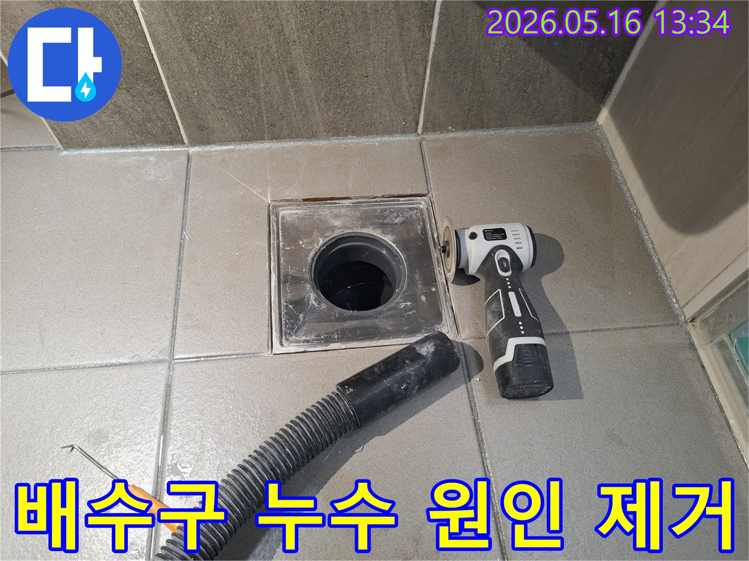 전문 엔지니어가 욕실 배수구 주변의 누수 원인을 제거하기 위해-전동 공구로 낡은 마감재를 긁어내고-흡입 호스로 잔해물을 빨아들이는 중입니다