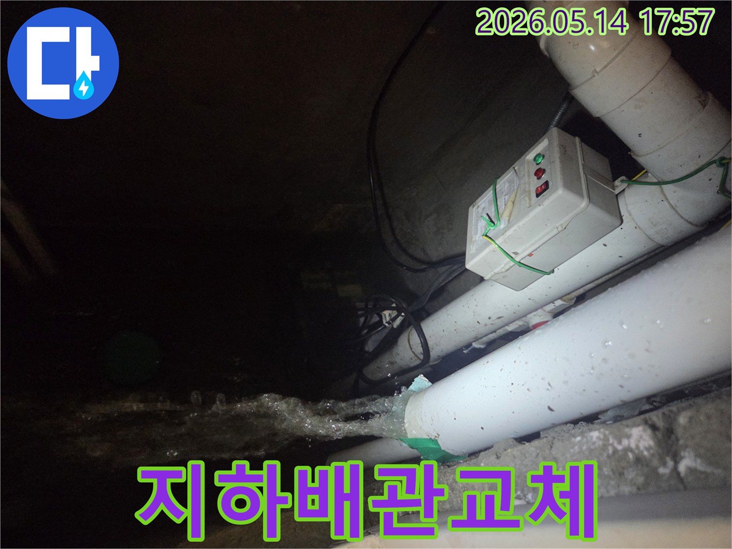 어두운 지하 공간에서-파이프에서 물이 힘차게 뿜어져 나오는-심각한 누수 현장을 보여주는 사진입니다-전기 제어 박스와 배관들이 주변에 보입니다.