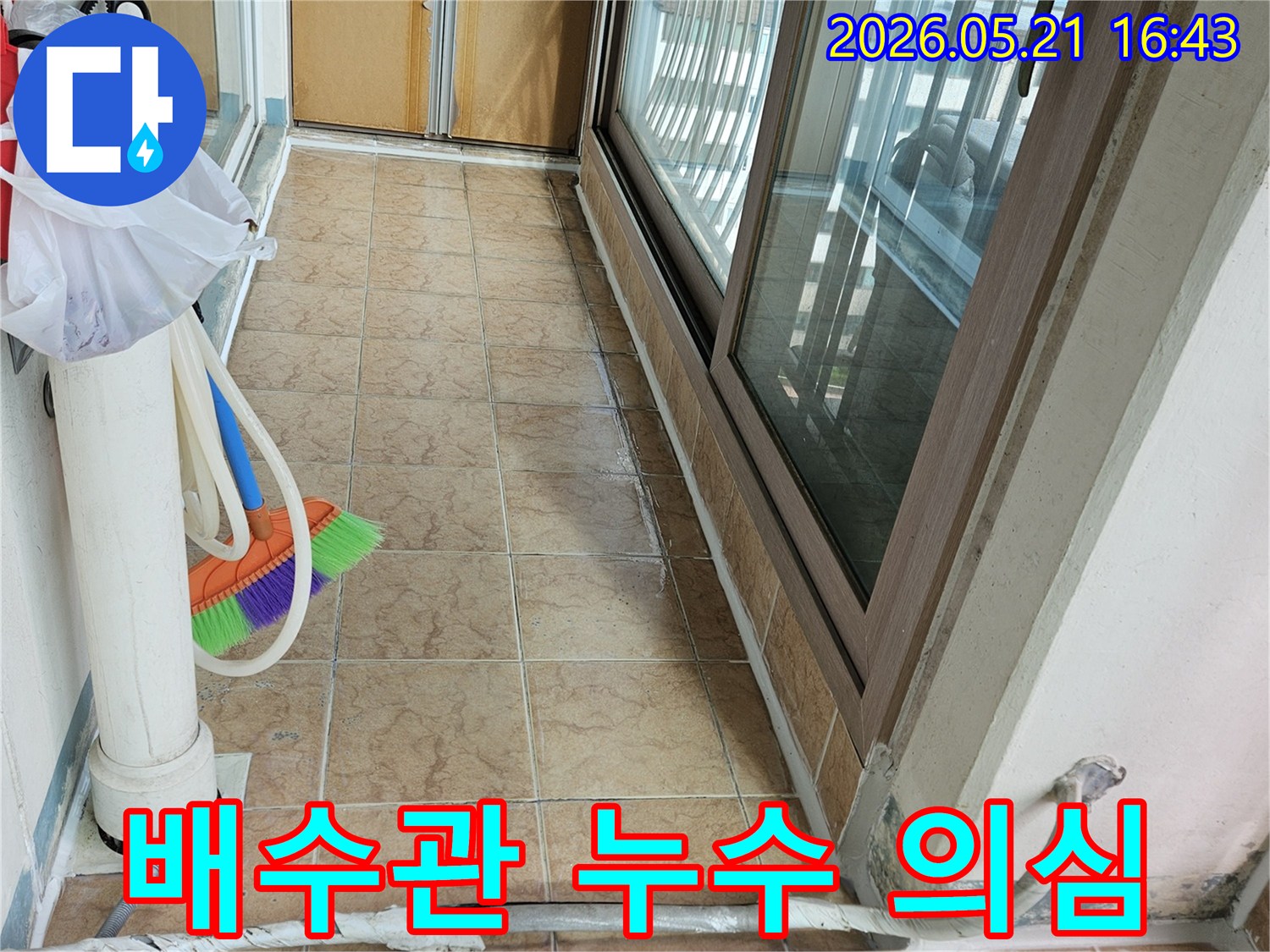 아파트 베란다의 큰 배수관과-주변 벽면 타일을 보여주며-배수관 주변 누수 여부를 점검하는 현장입니다.