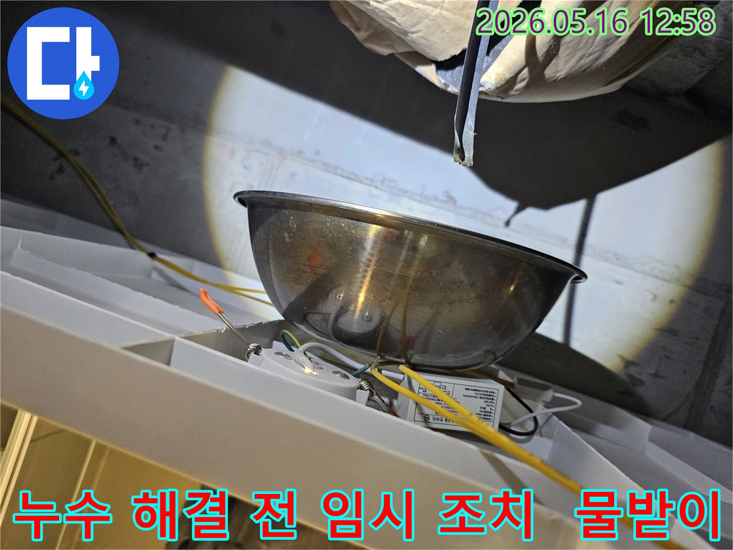누수 해결 작업을 시작하기 전-천장에서 물이 떨어지는 것을-스테인리스 볼로-받아내며-주변의 전기 배선과-조명 장치를-보호하는 모습