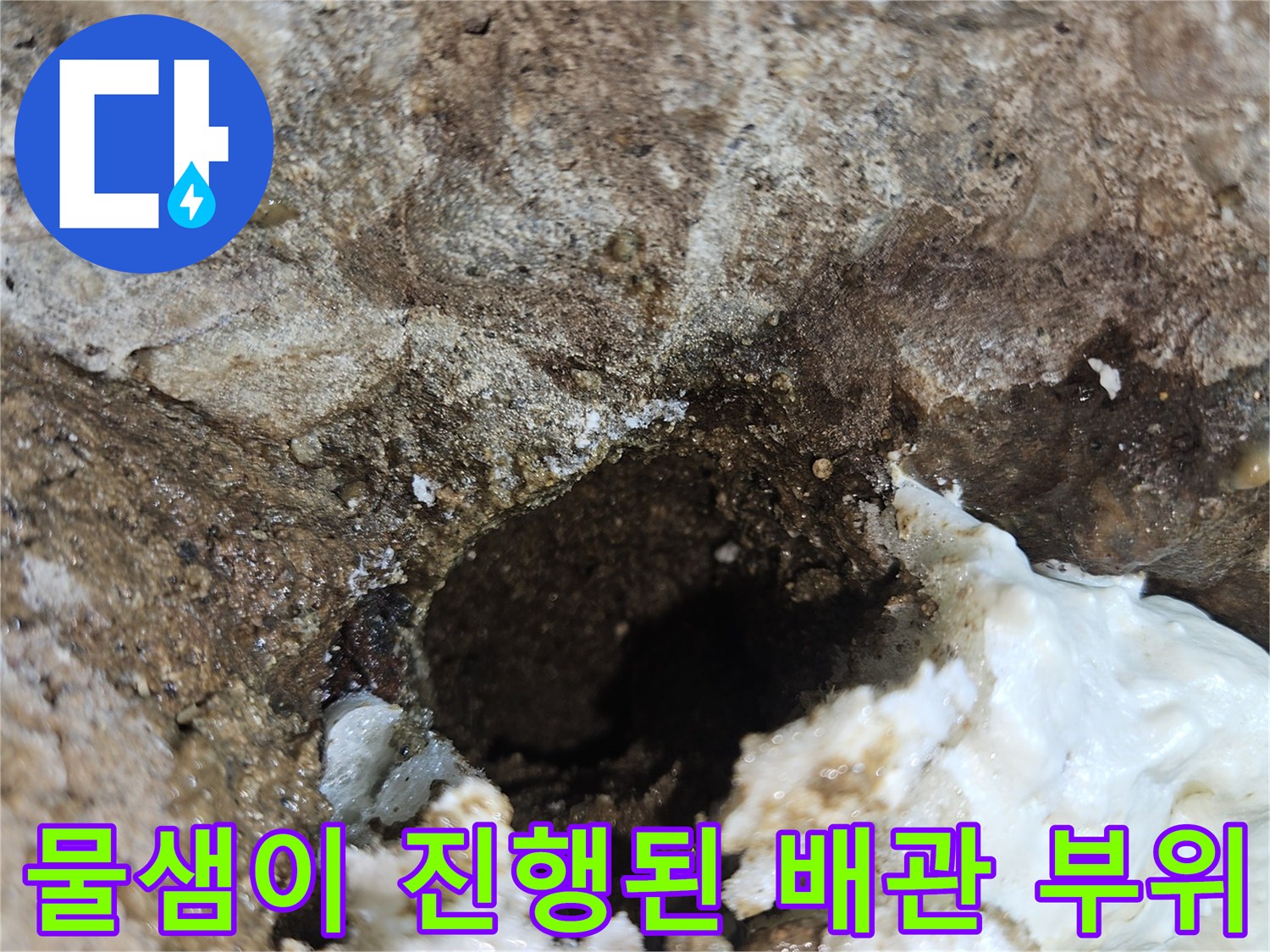 하얗게 변한 이물질과 젖은 콘크리트가 보이는 배관 주변 사진입니다.