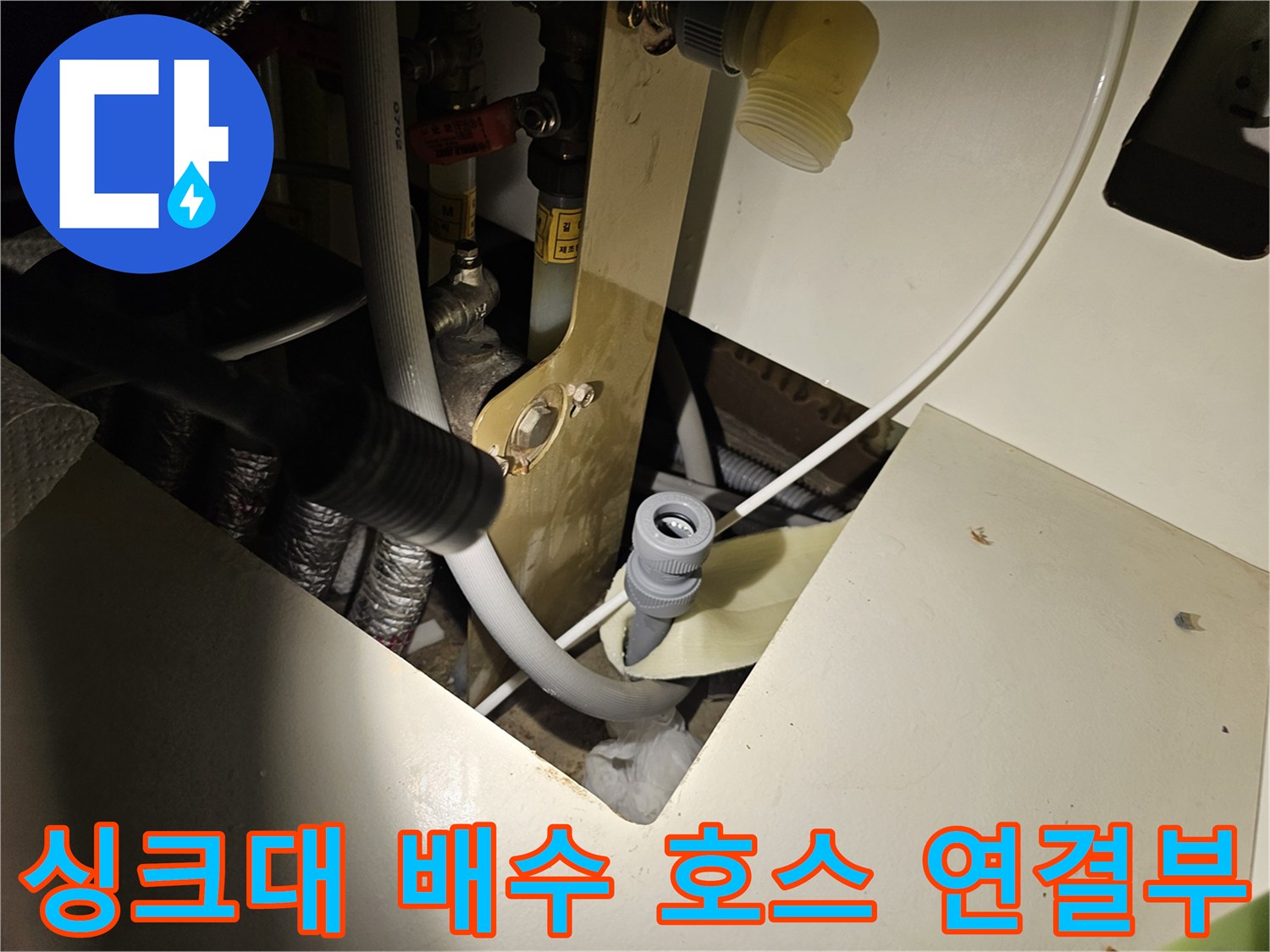 하부장 내부에 노출된 흰색 배수 호스와 관통 지점