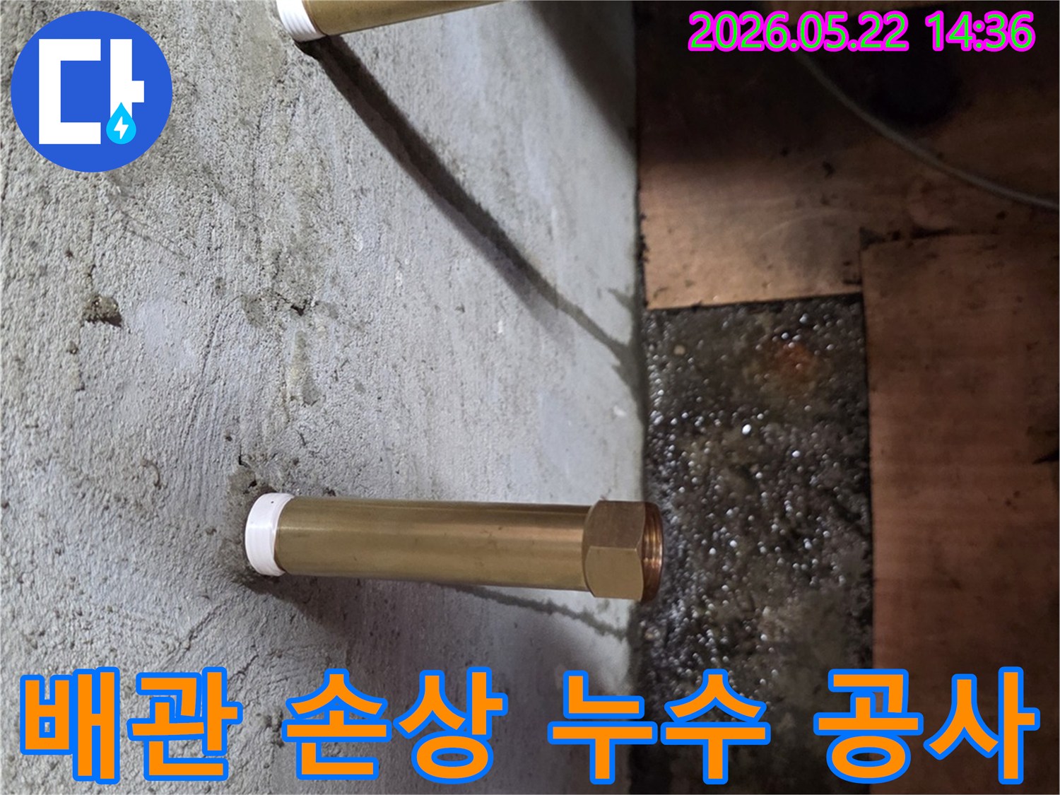 천장에서 내려온 금속 배관 아래로 물이 고여있는-배관 손상으로 인한 누수 공사 현장을 보여주는 이미지입니다.