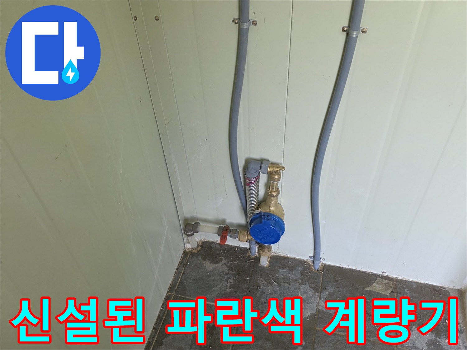 수직으로 내려오는 배관에 연결된 파란색 수도 계량기