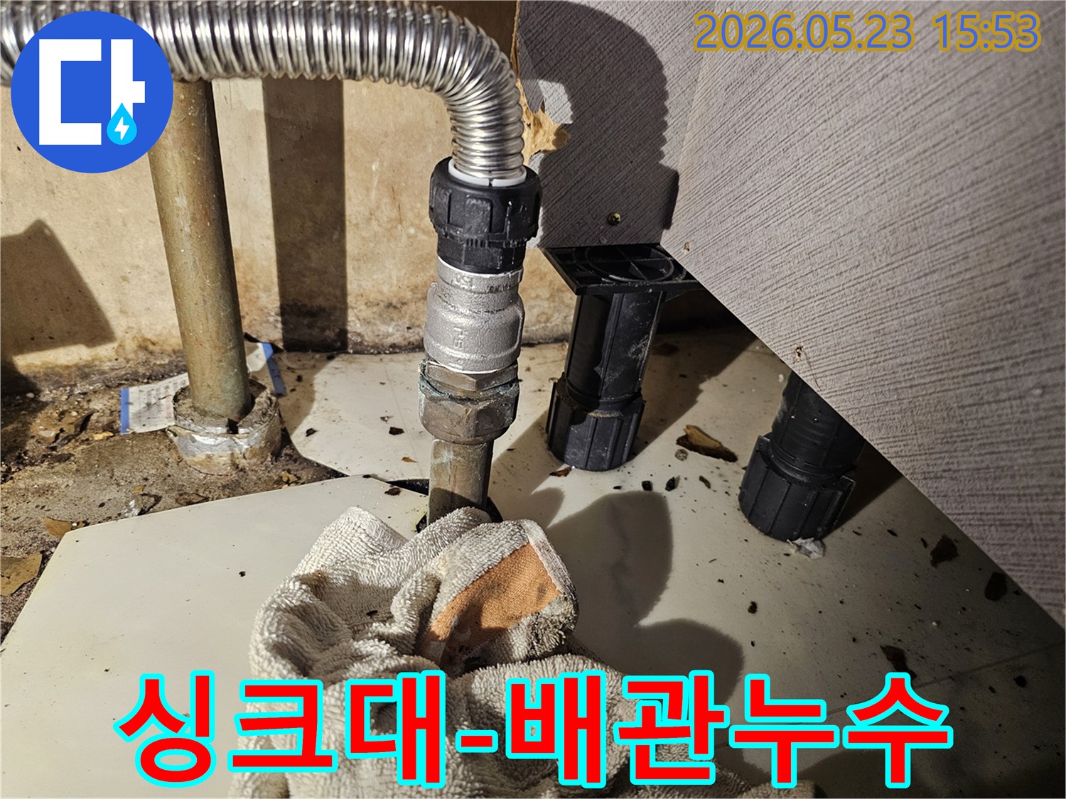 싱크대 하부의 배관 연결부에서 물이 새어-바닥에 젖은 수건이 놓인-긴급 누수 현장