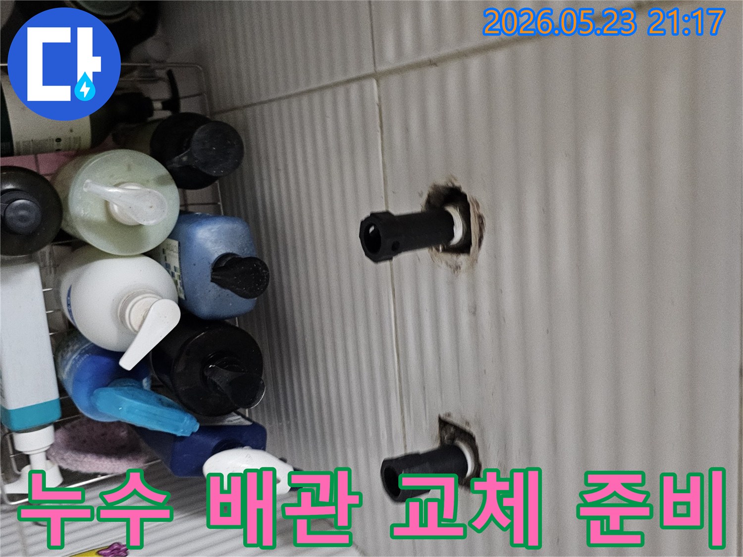 타일 벽면에서 노출된 수도 배관의 연결 부위를-누수 재발 방지를 위해 새 배관으로 교체하기 위해-준비하는 모습입니다.