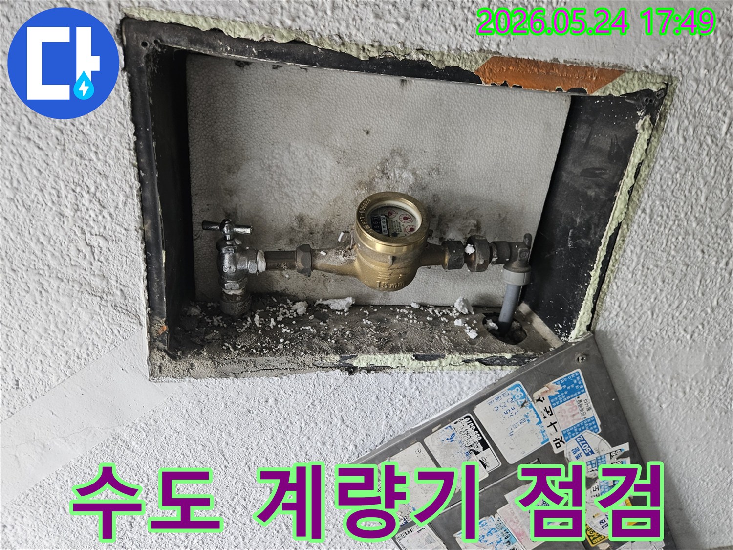 벽에 매립된 수도 계량기와-주변 배관의 상태를-면밀히 점검하는 모습입니다.