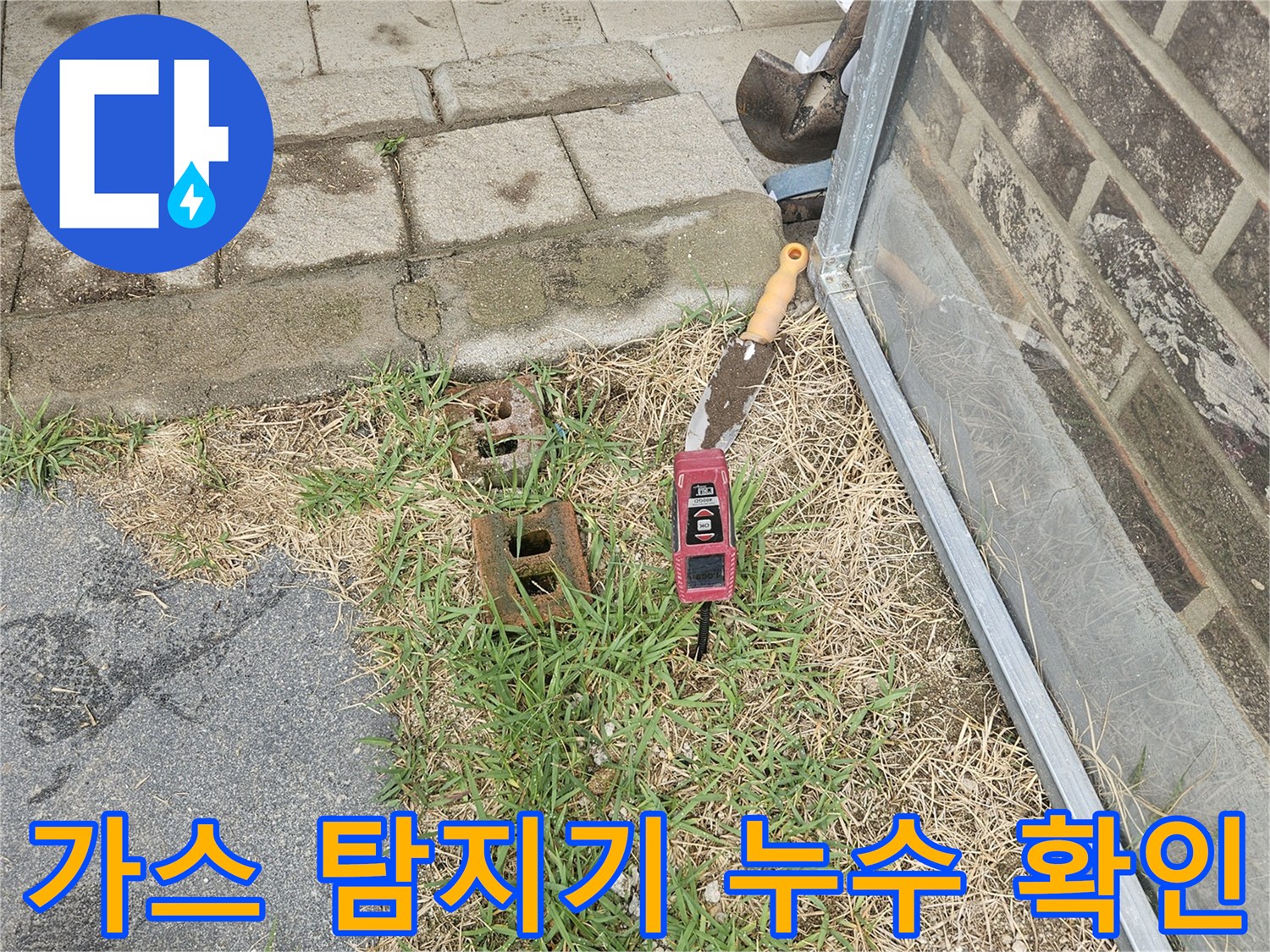 마당 바닥에서 가스식 탐지기를 사용하여 배관의 물샘 지점을 찾는 장면입니다.