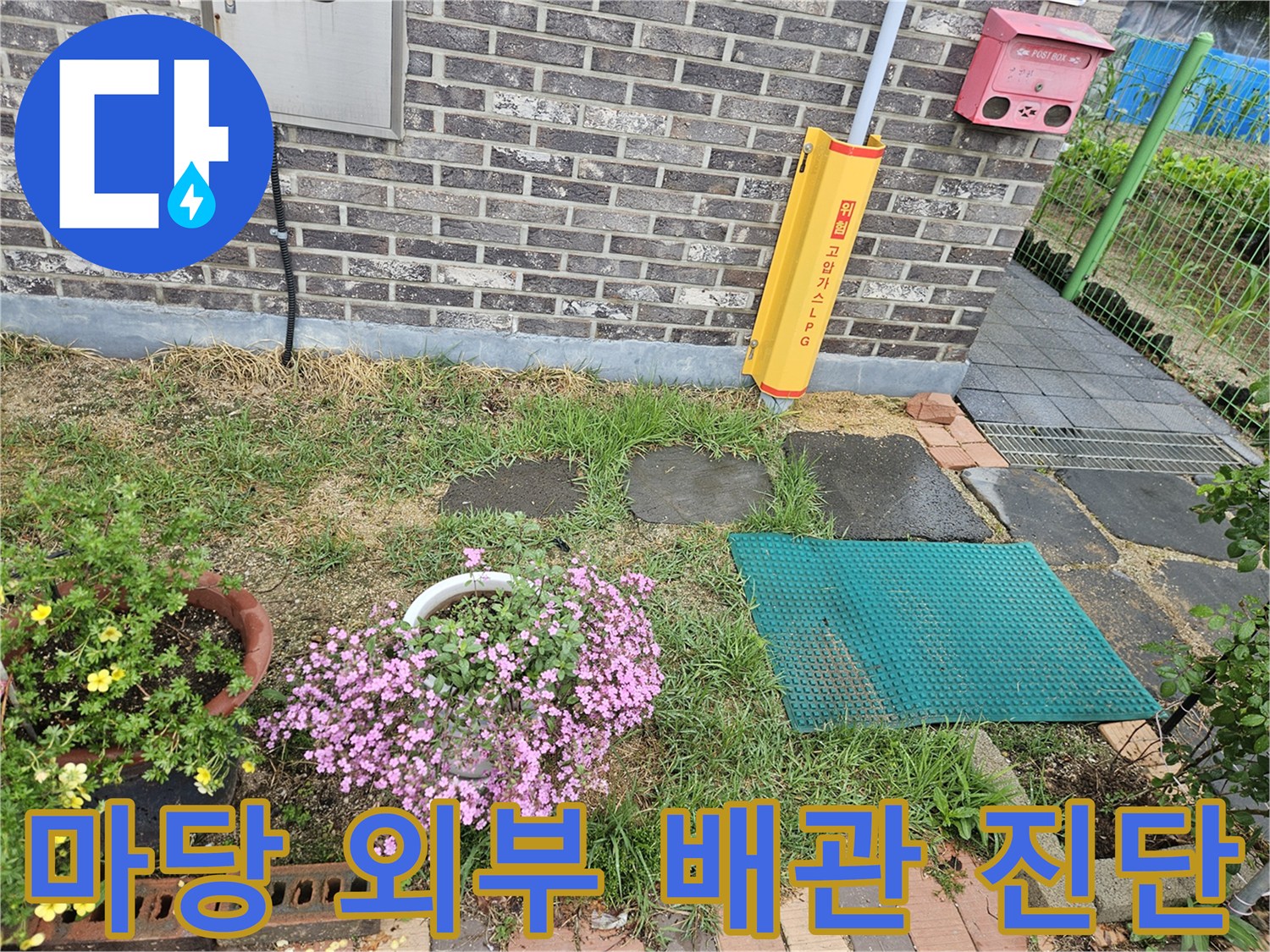 벽돌 벽면 아래 설치된 외부 급수 시설과 주변 지면의 모습입니다.