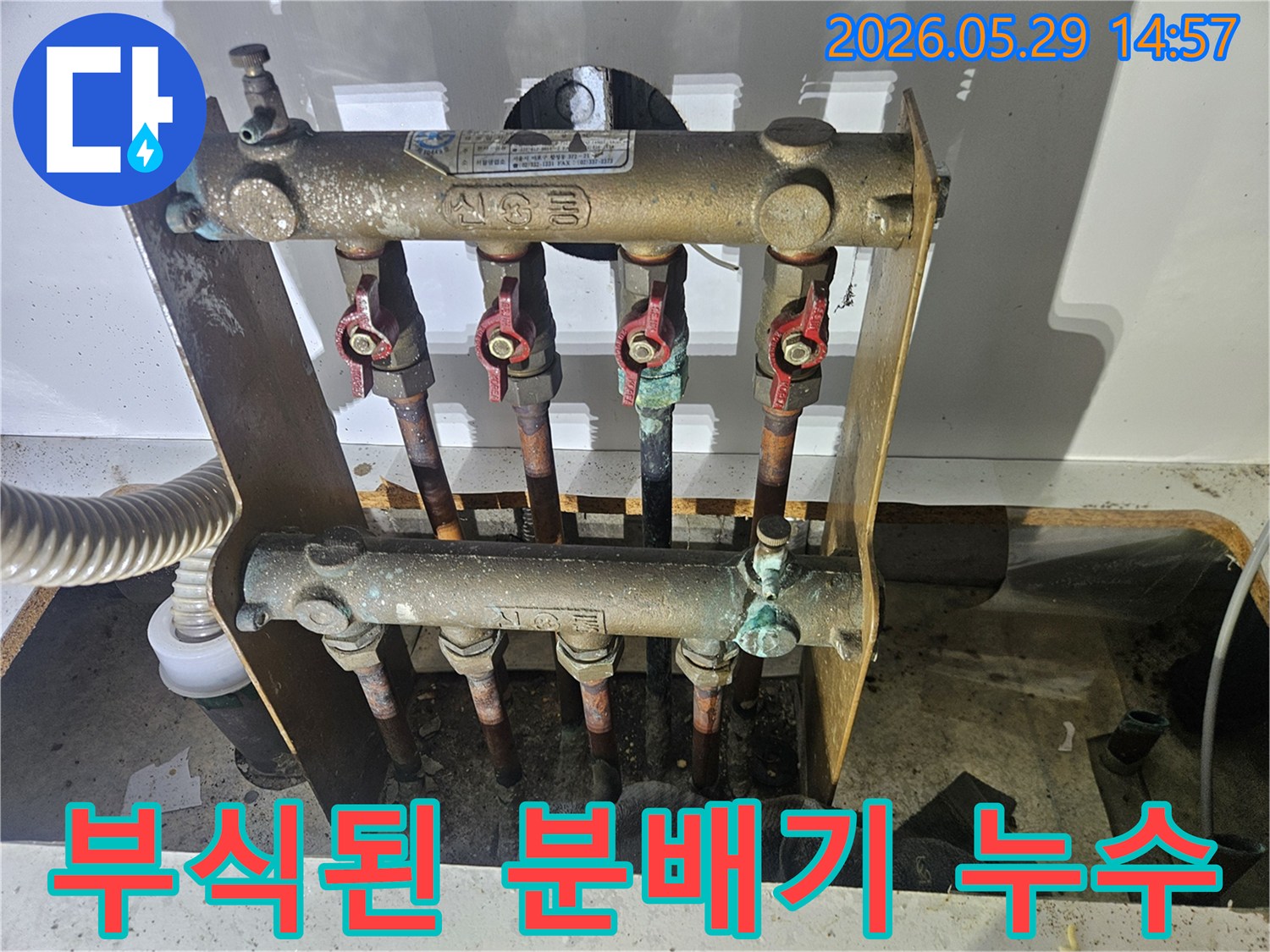 오래된 아파트의 난방 분배기에서-심각한 부식과 함께 누수 흔적이 발견되어-전문가가 교체 작업을 준비하고 있습니다.