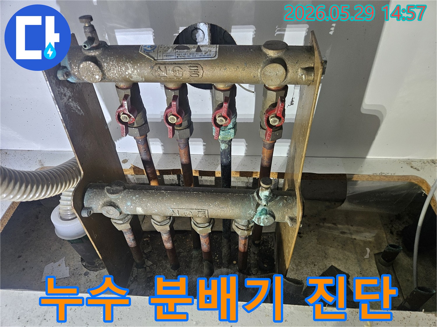 오래된 아파트의 난방 분배기에서-심각한 부식과 함께 누수 흔적이 발견되어-전문가가 교체 작업을 준비하고 있습니다.