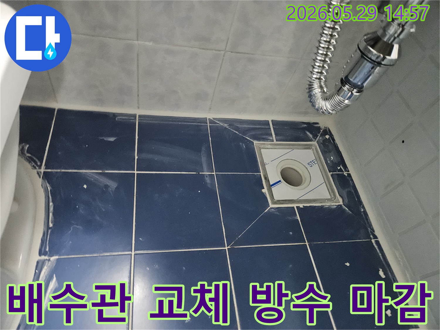 욕실 바닥의-새로운 배수구와-주변 타일-그리고 견고하게-연결된 유연한-배수관이-보이는-누수-해결-현장-사진입니다