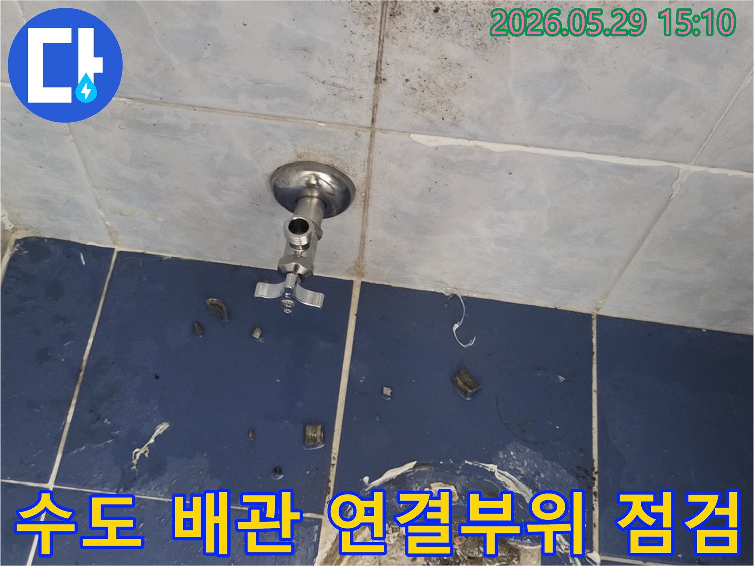 욕실 벽면에 설치된 수도 밸브와-그 주변의 누수 여부를-면밀히 점검하고 있는 모습입니다